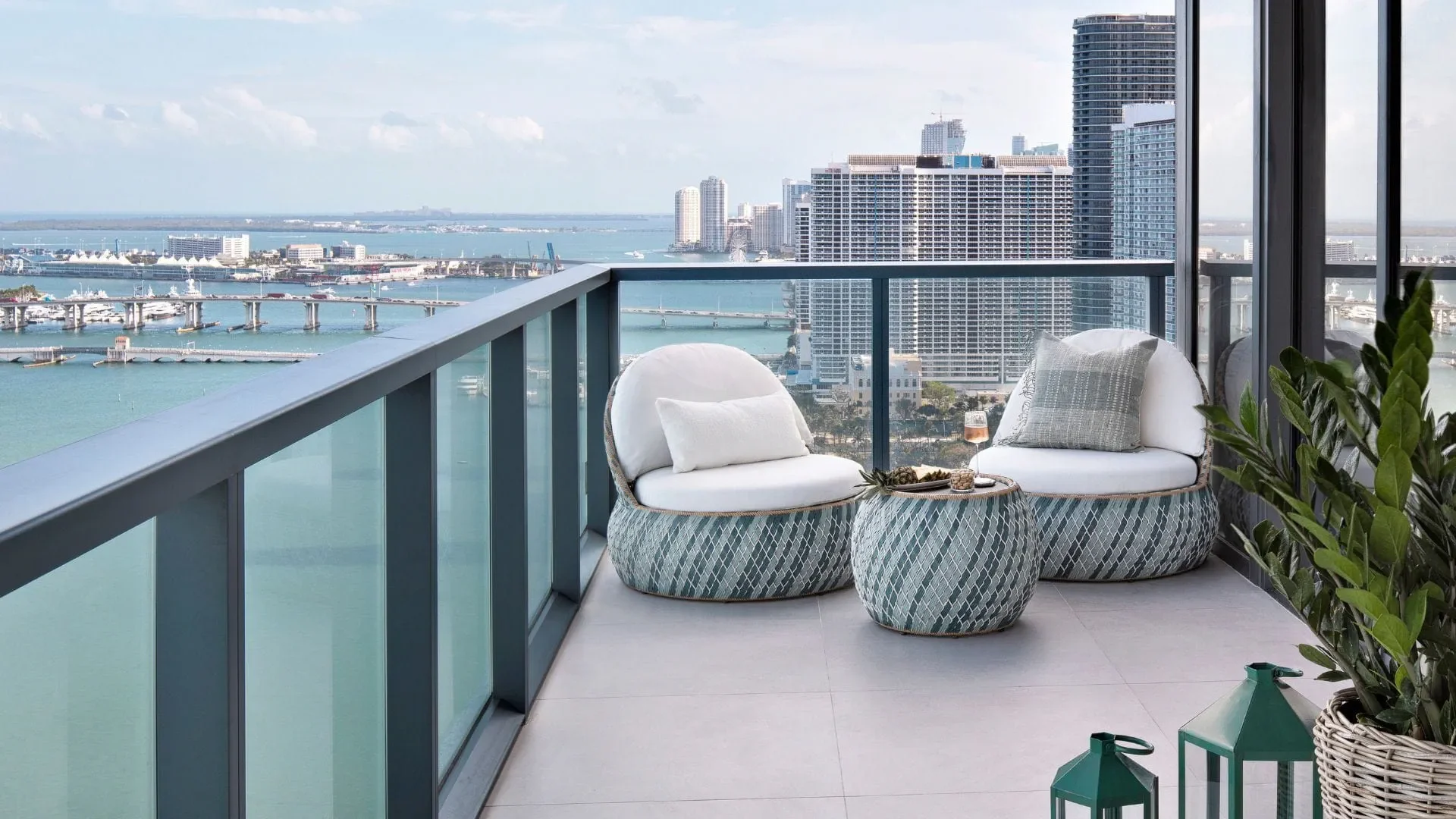 Balcony with modern seating and view of a city skyline, harbor, and water.