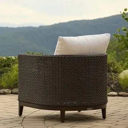 Outdoor wicker chair with a cushion, overlooking a mountain landscape.