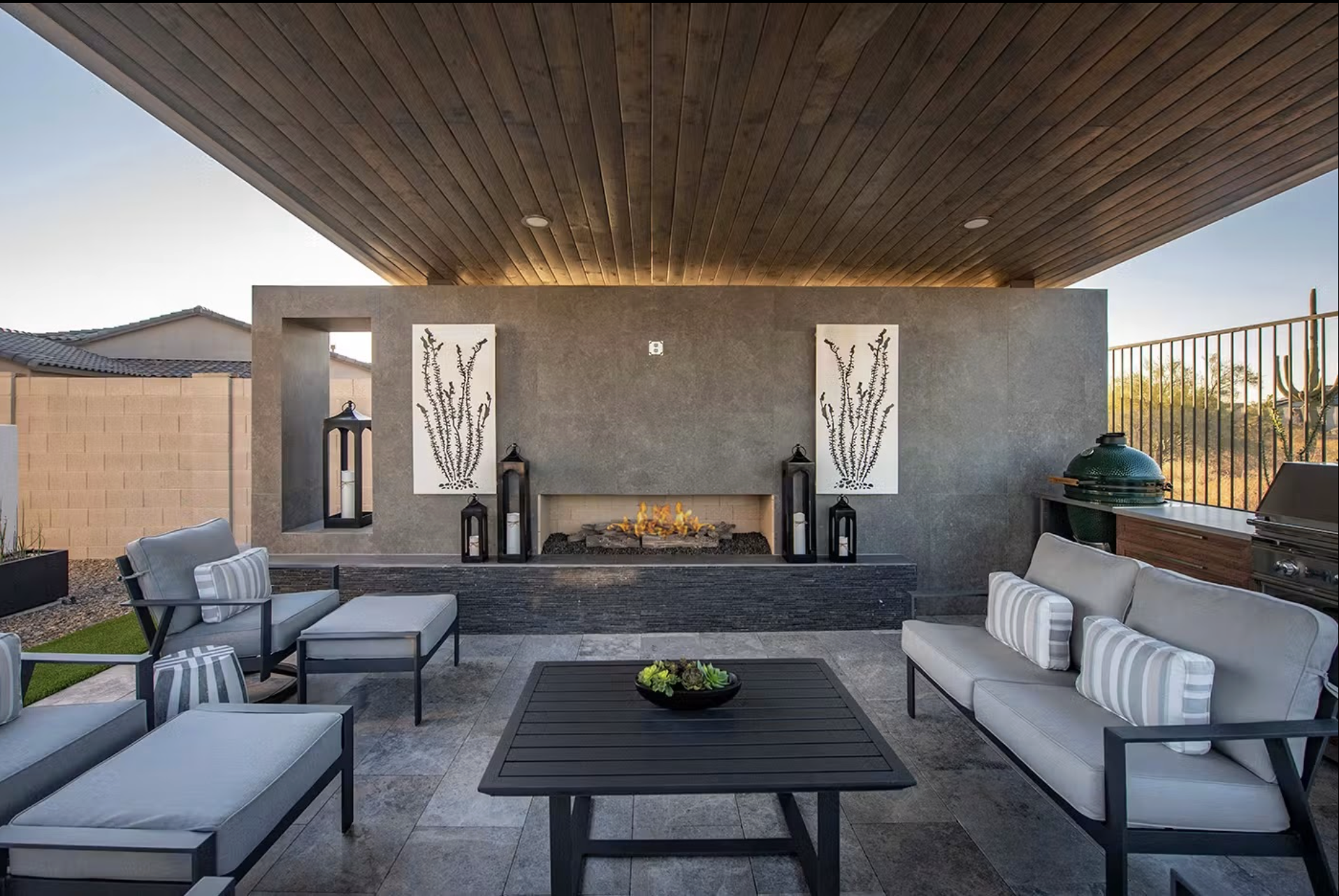 Outdoor patio area with a modern fireplace, seating, and decorative elements under a wooden ceiling.