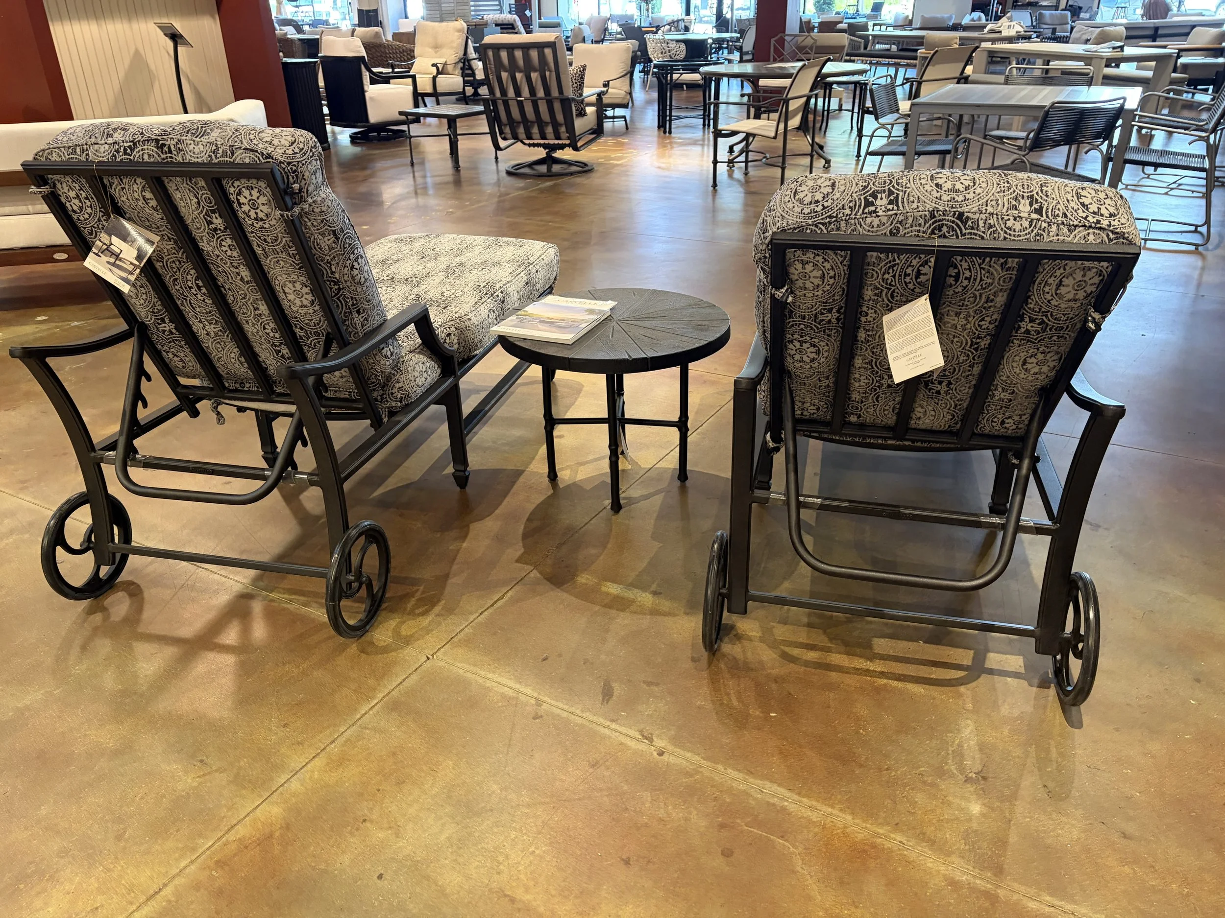 A furniture showroom displays various chairs, tables, and upholstery on a polished concrete floor.