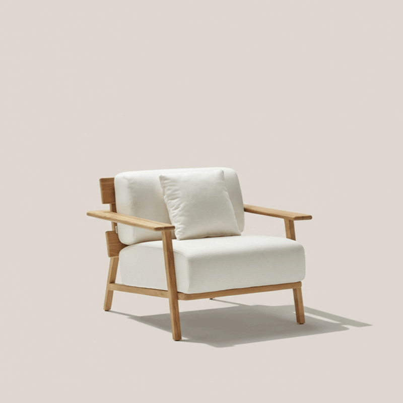 A modern white armchair with wooden armrests and legs, with a matching white cushion, against a plain light beige background.