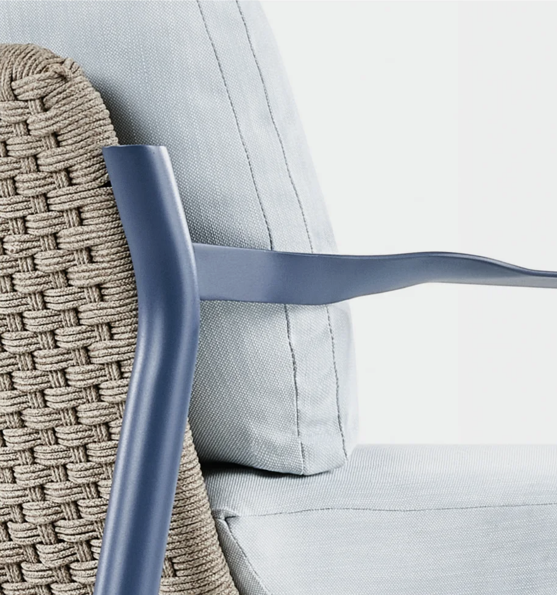 Close-up of a wicker-backed chair with a gray armrest and a gray cushion.