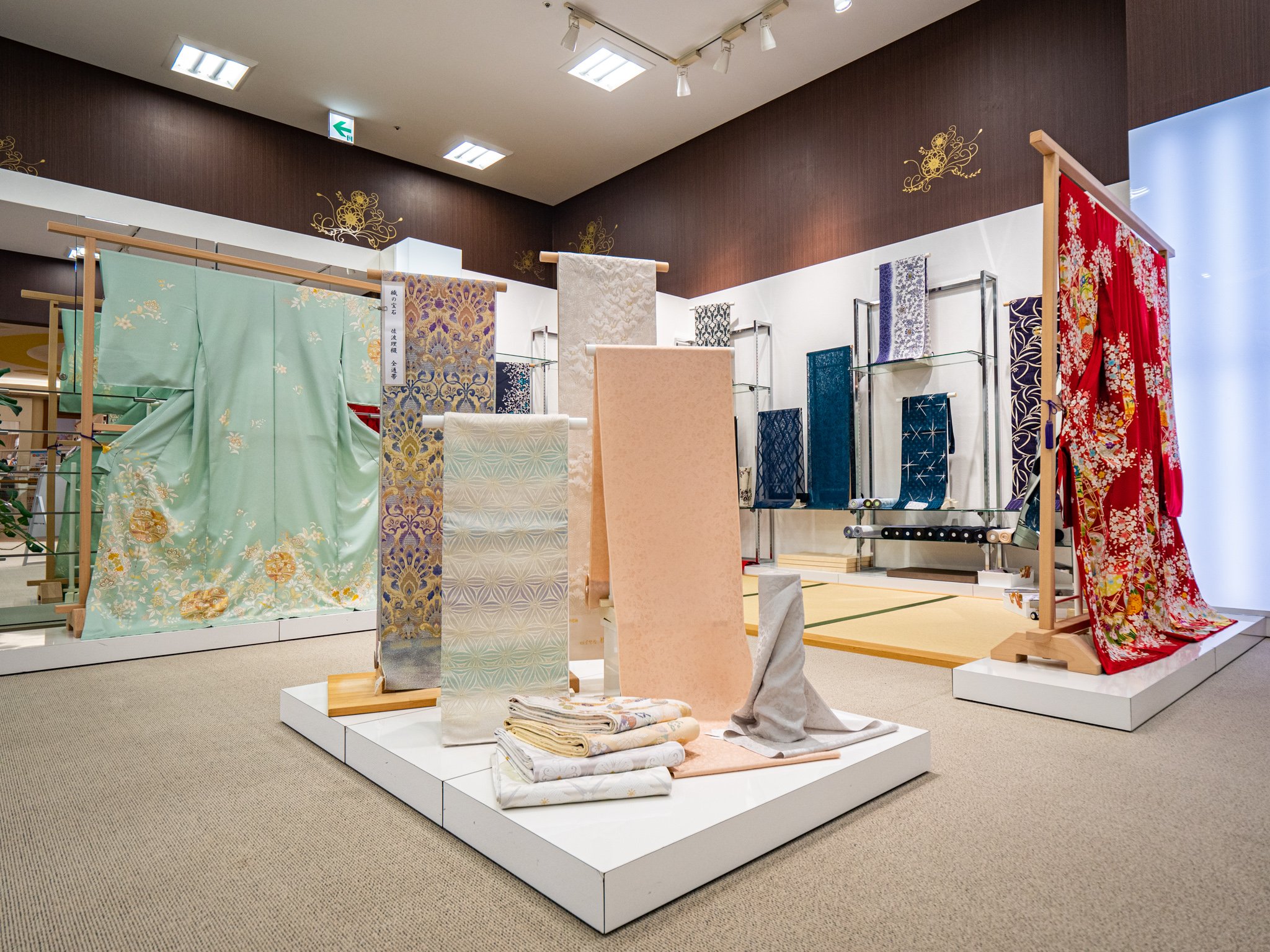 着物の展示会場で、さまざまな柄と色の着物や帯が展示されている