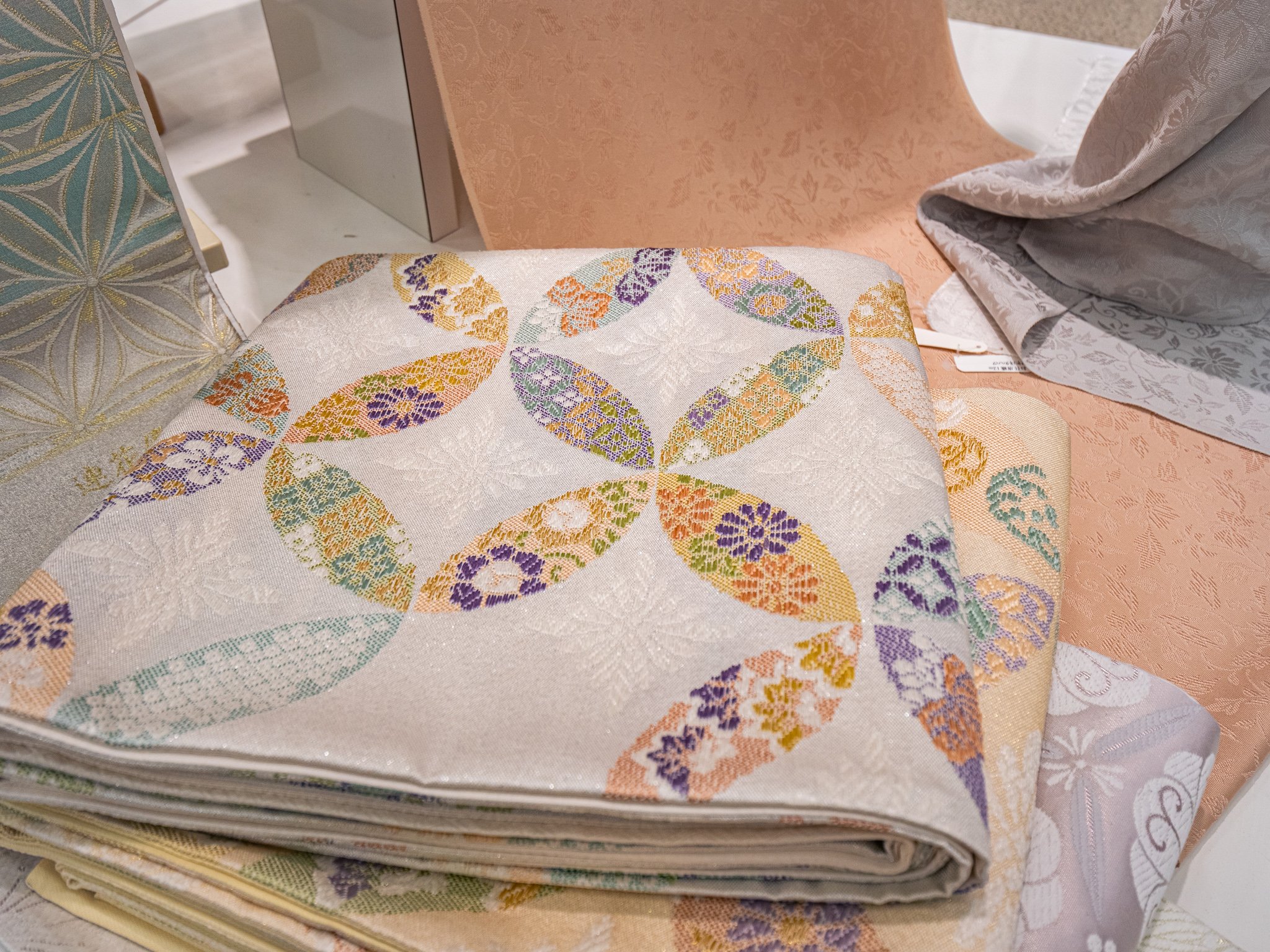 さまざまな色と模様の刺繍が施された布地が山積みされている。