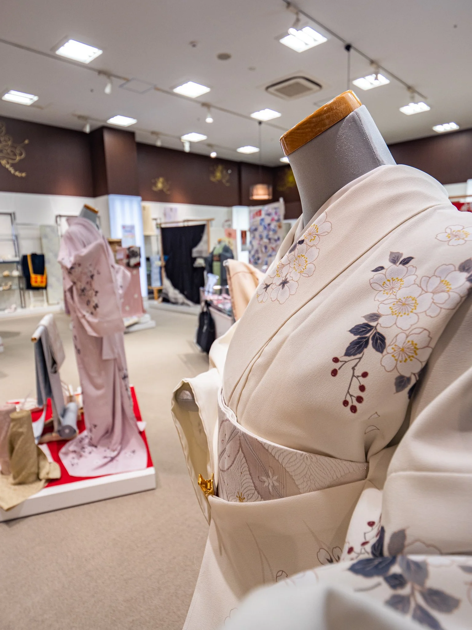 着物の展示品が並ぶ室内ショーケース。白地に花柄の着物が中心。