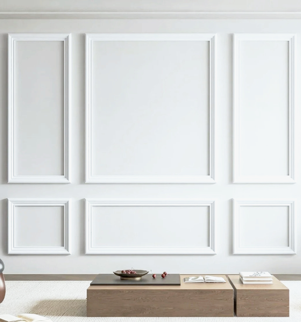 Minimalist living room with white paneled wall, wooden coffee tables, and a book and bowl on the tables.