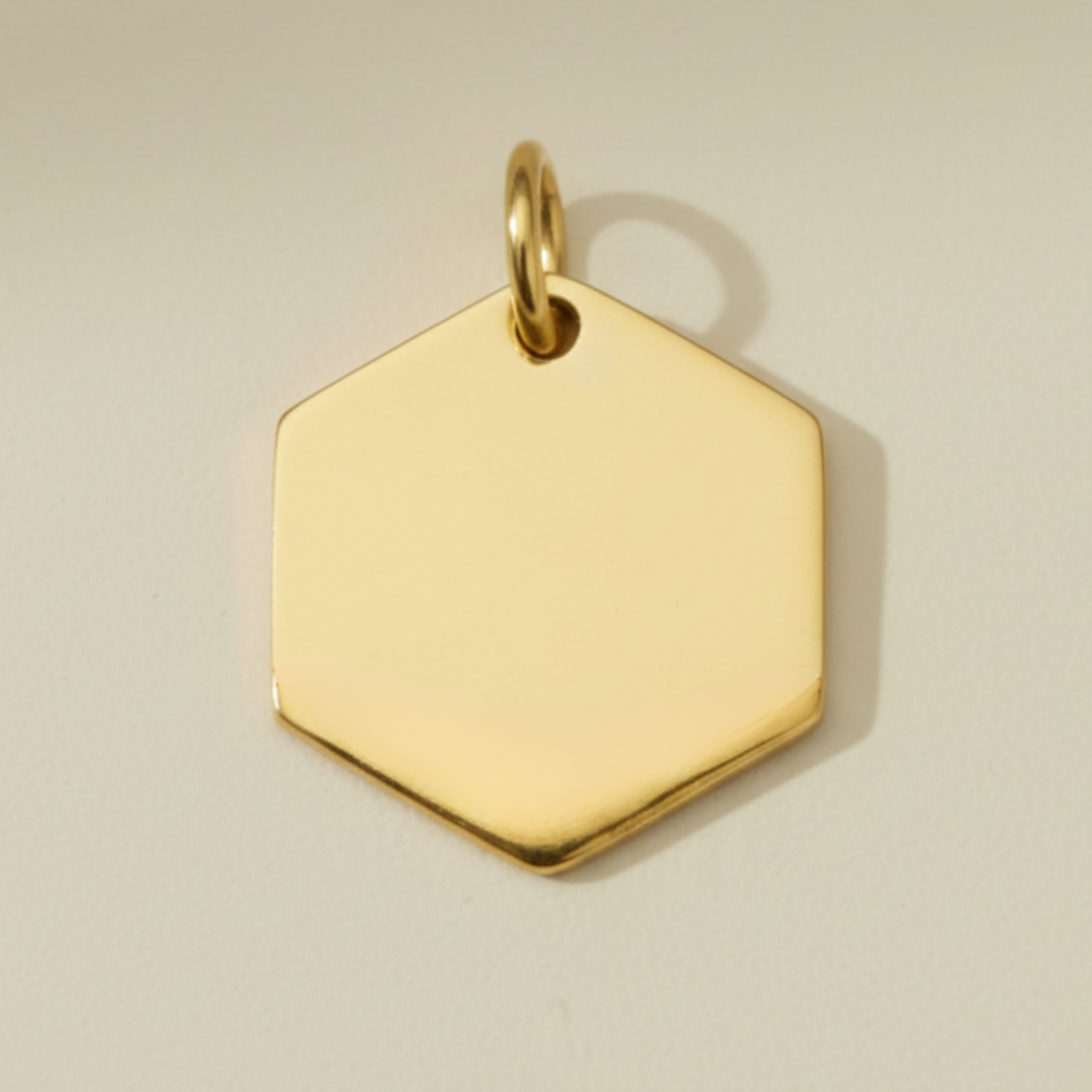 A blank 18k gold pvd hexagon-shaped charm pendant with a jump ring attached