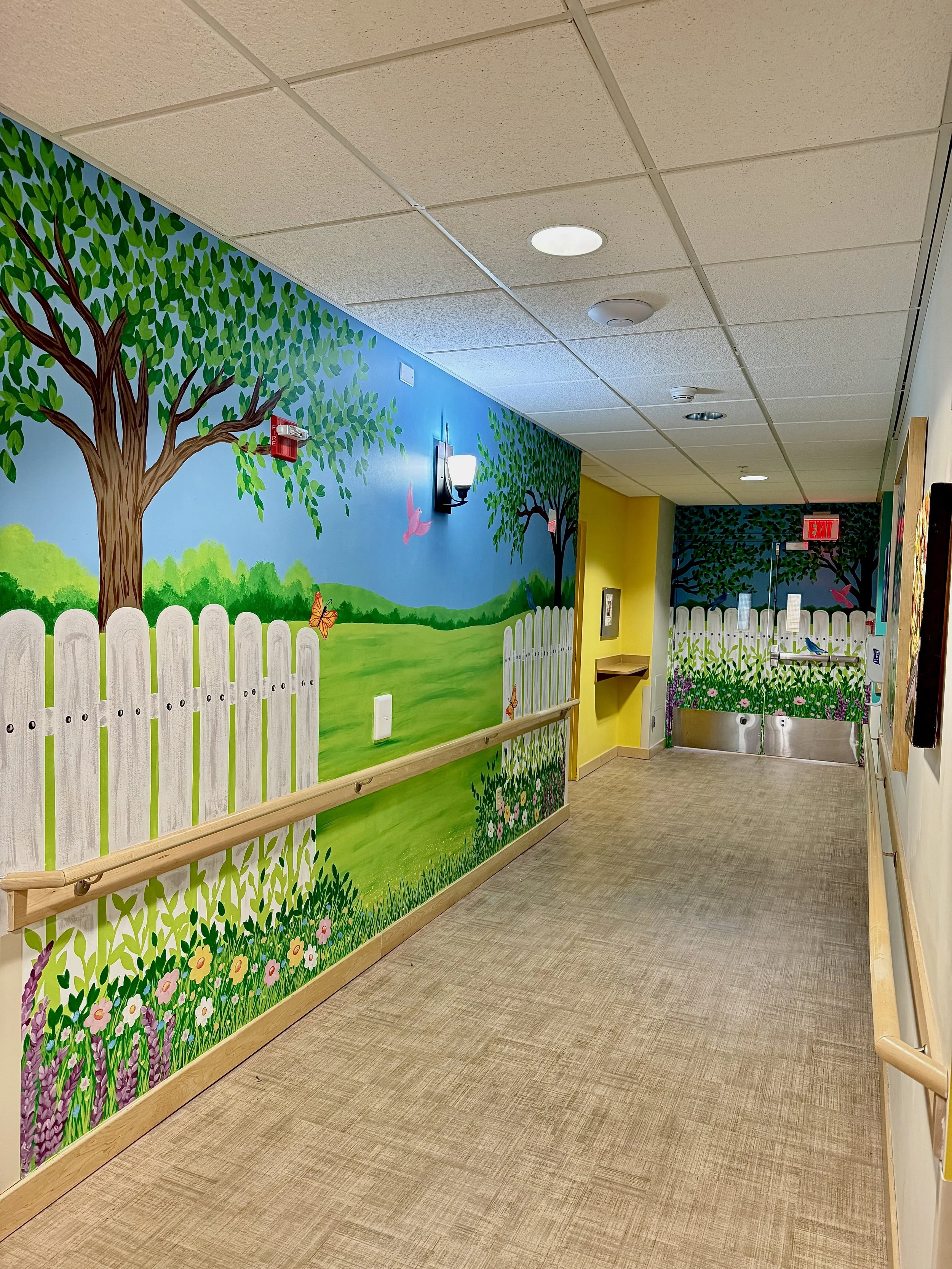 Dementia Ward scenic mural featuring a green field with trees and a fence with flowers and a butterflies and birds