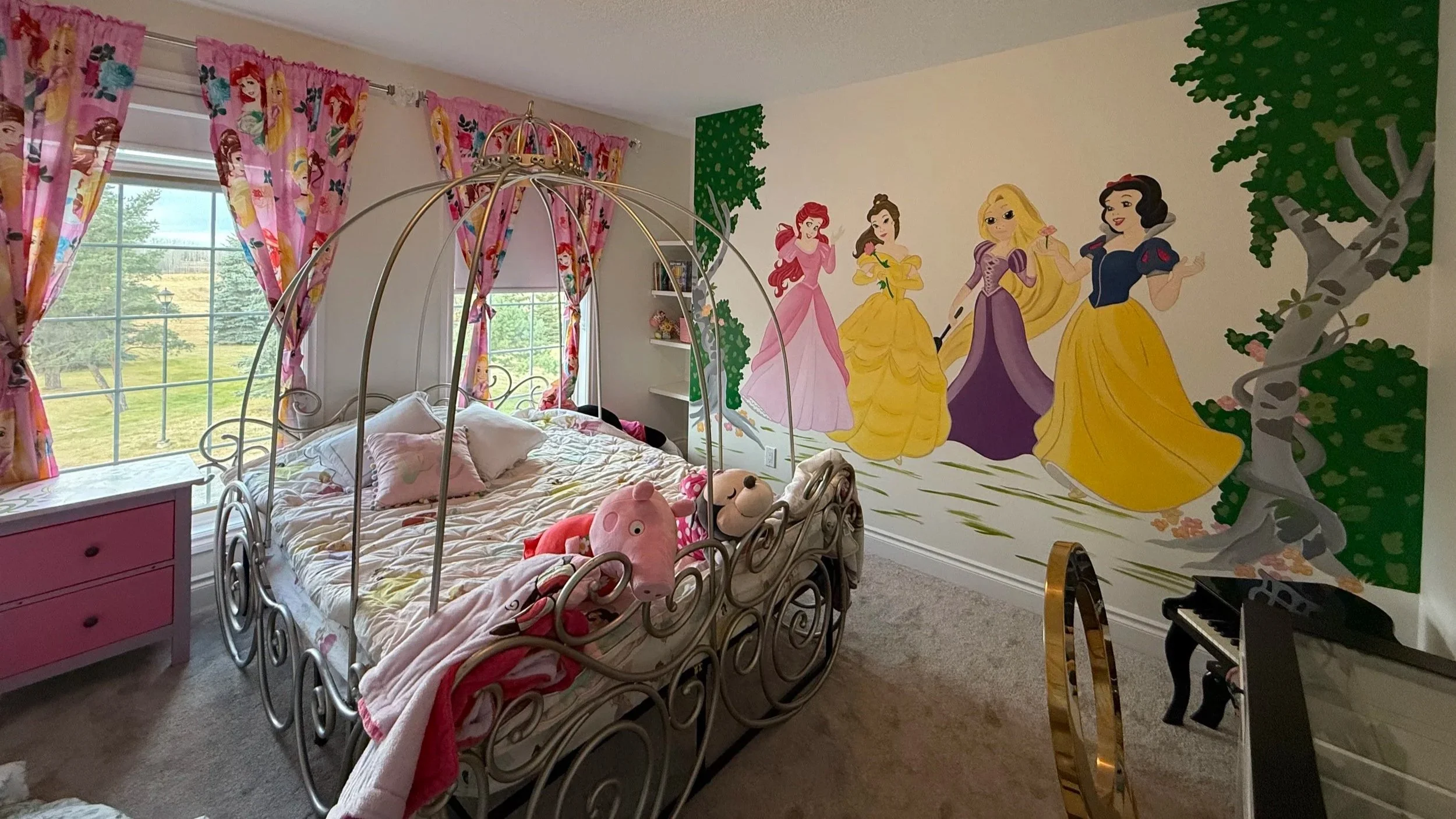 Hand painted Disney princess mural featuring Snow White, Ariel, Tangled, and Belle on childs room wall with green and gray trees cinderella bed and Disney princess curtains