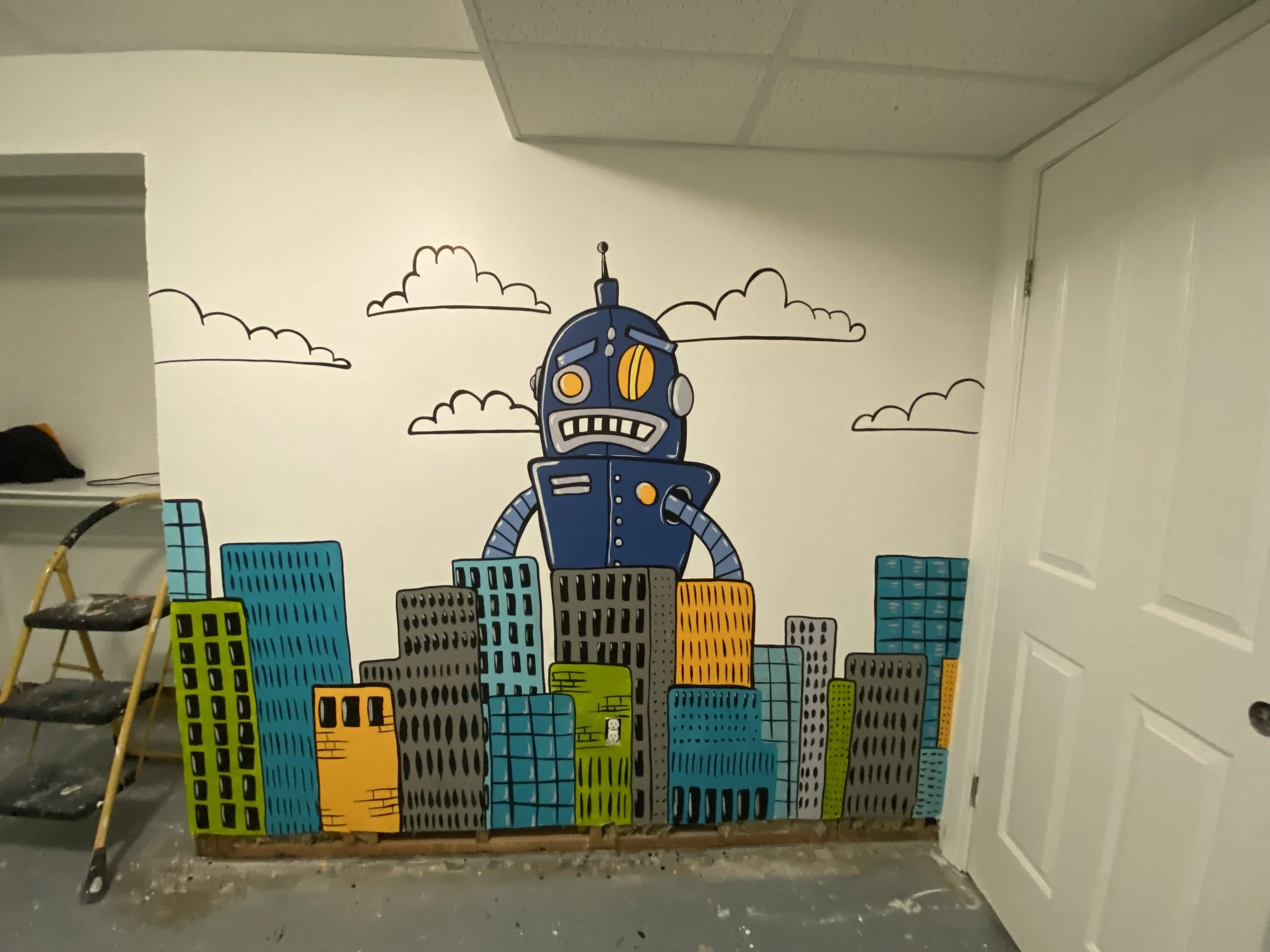 A colorful mural of a cartoon robot standing atop a city skyline with clouds in the background, painted on an interior wall.