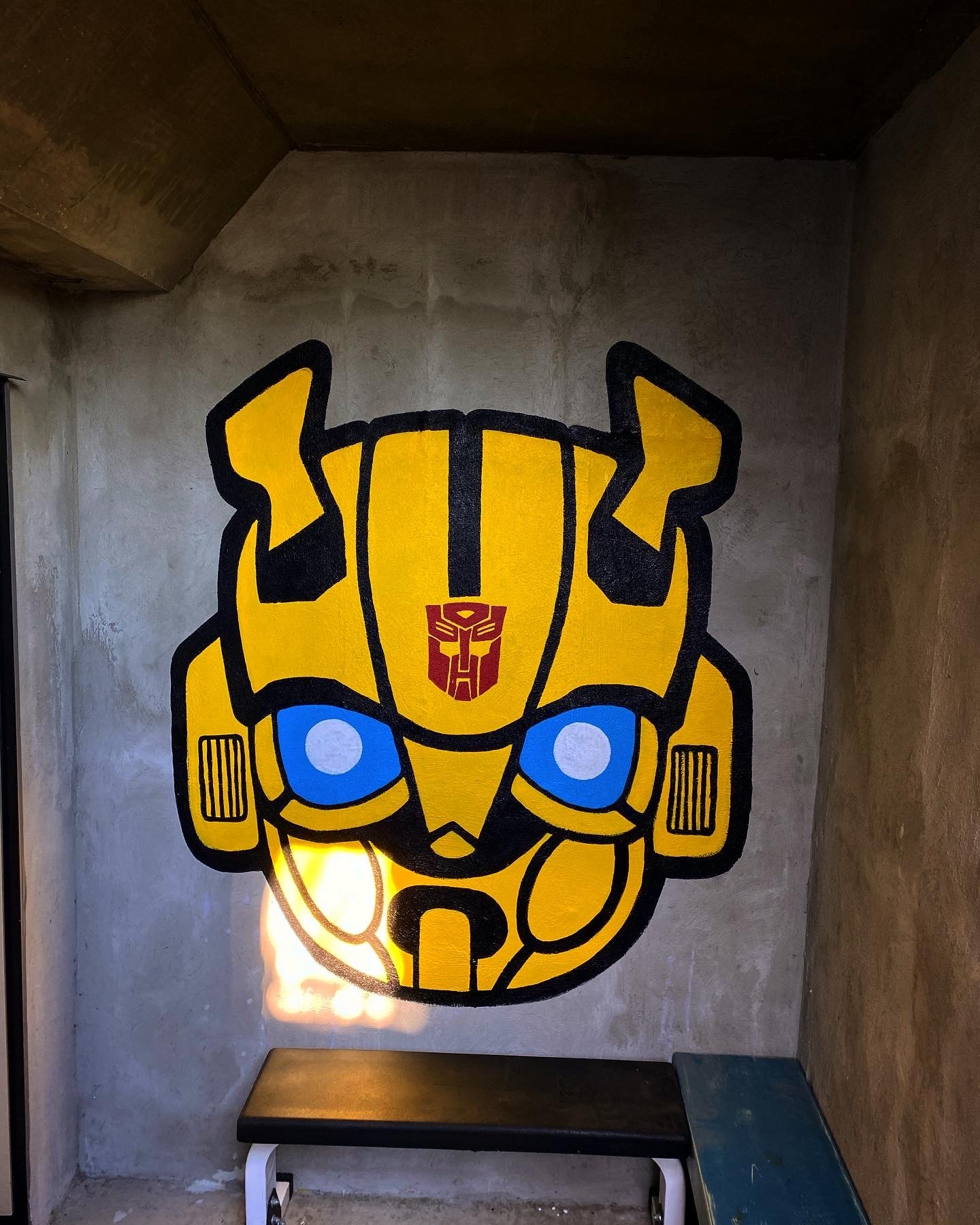Large Transformers Bumblebee head mural located on concrete wall of the basement suite in Edmonton, AB painted by artist Carly Marie Murals