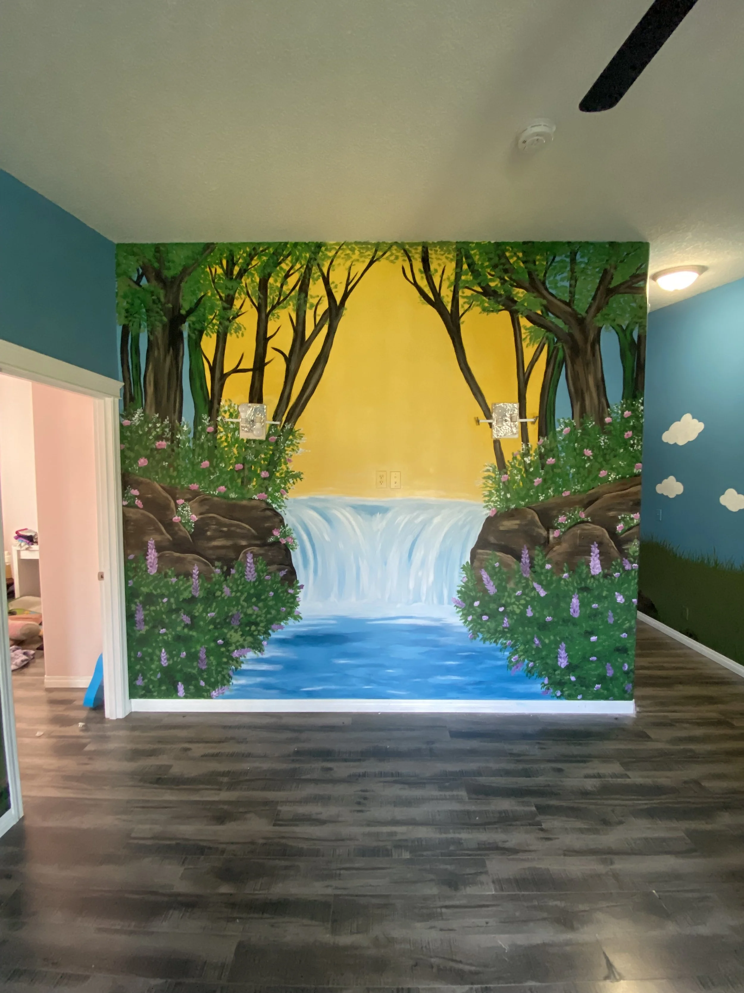 Residential mural located in Parkland day home featuring waterfall mural with treeline and waterfront. Edmonton, AB artist Carly Marie Murals