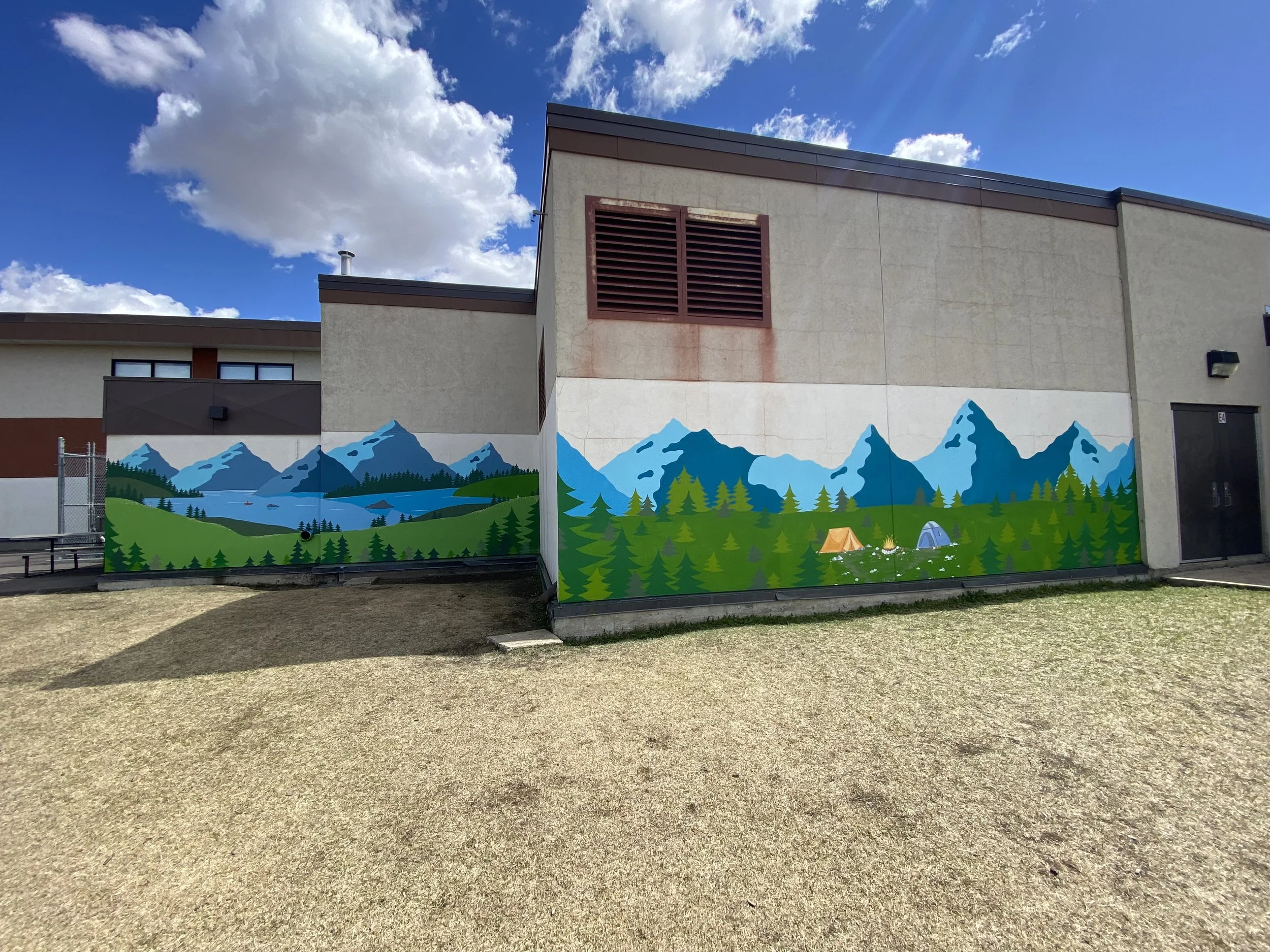 A colorful mural of mountains, trees, and tents painted on the wall of a building. The sky is partly cloudy with blue sky visible.