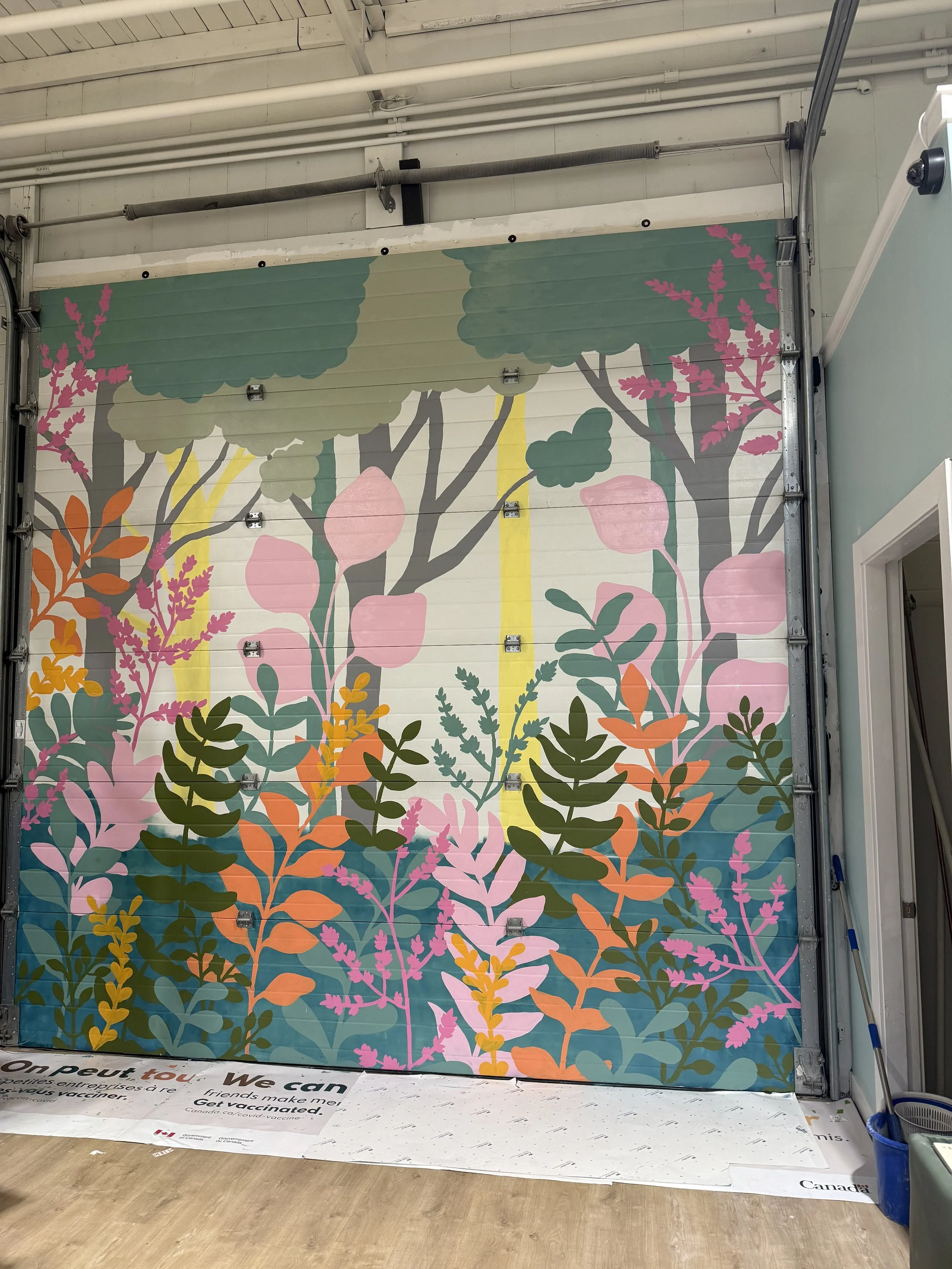 Hand painted floral mural with trees on garage door located in Edmonton, AB at Play Den Cafe
