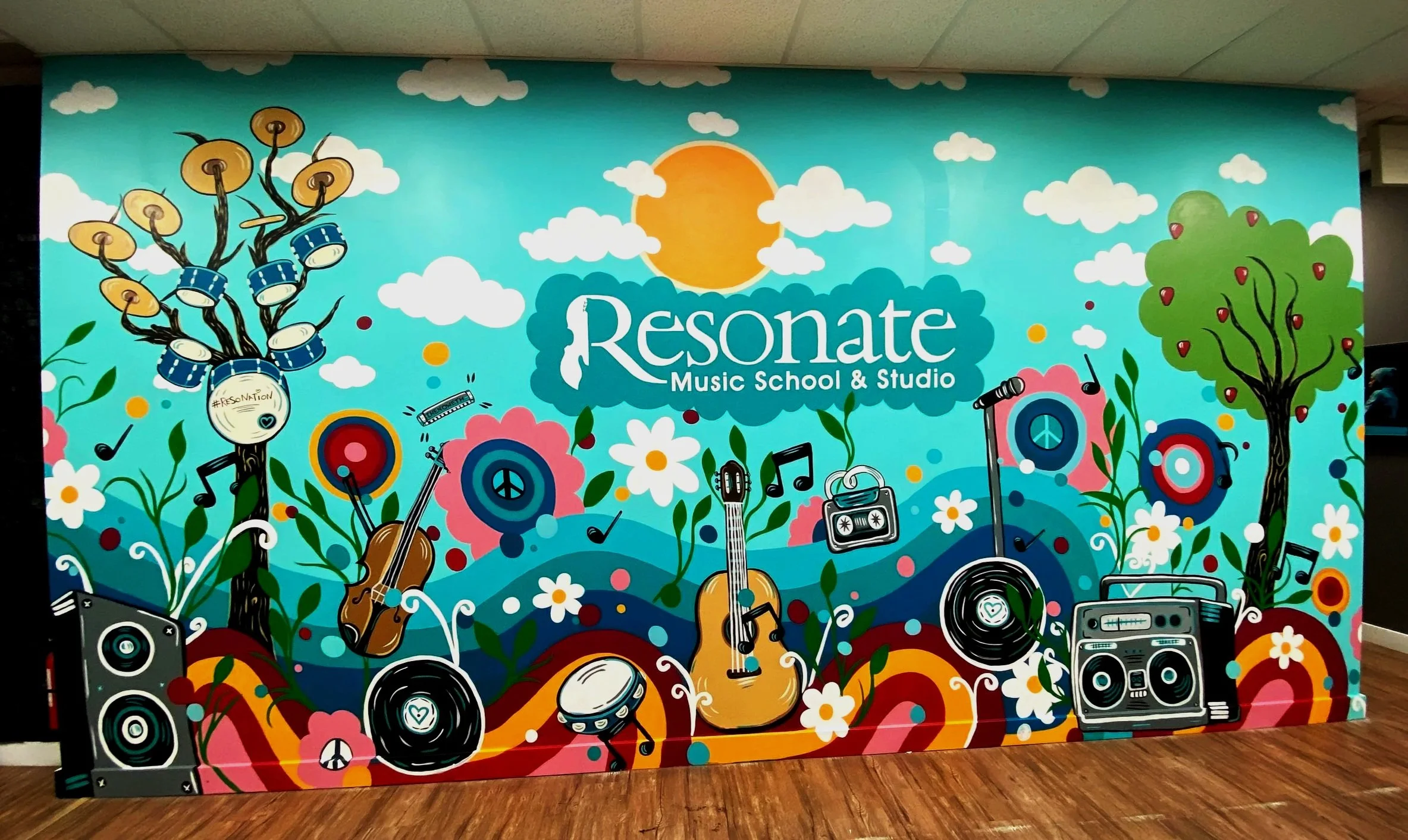 Colorful mural for Resonate Music School & Studio featuring illustrated musical instruments, speakers, trees, flowers, clouds, and a sun, with the studio's name in the center by Edmonton artist Carly Marie Murals.