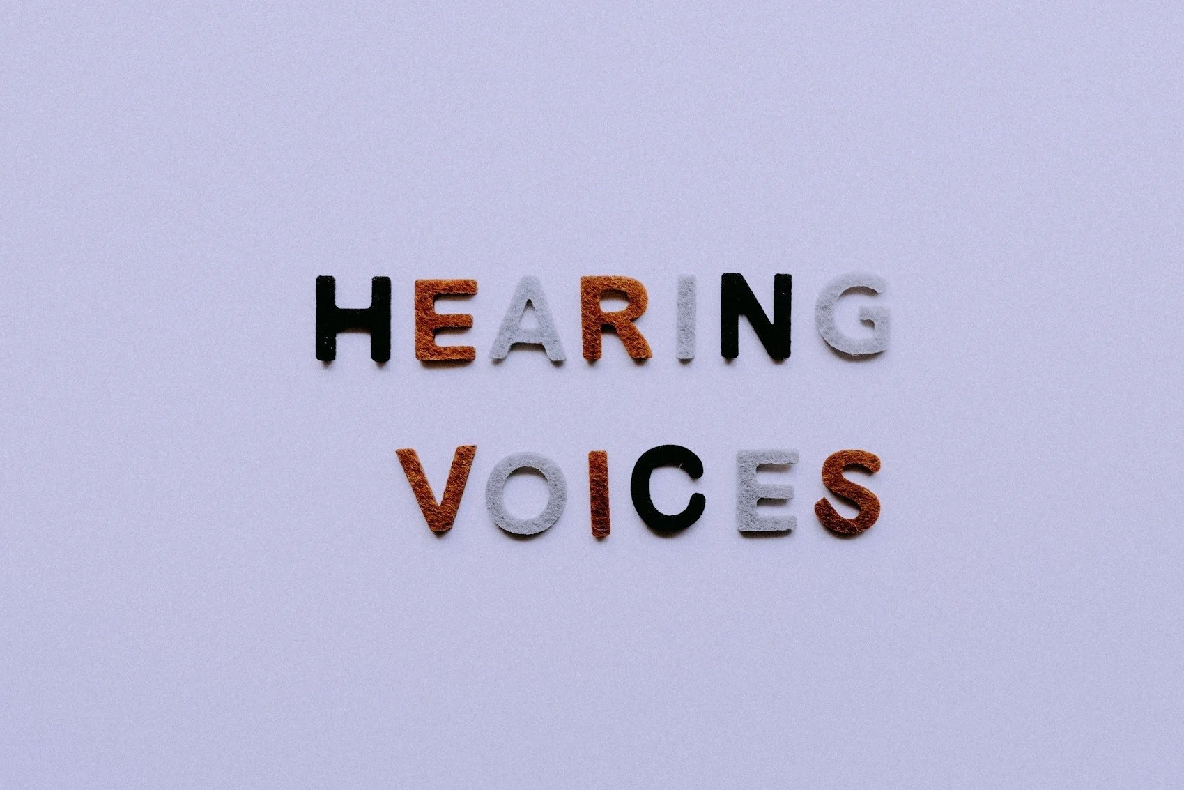 Letters spelling 'HEARING VOICES' arranged on a plain background.