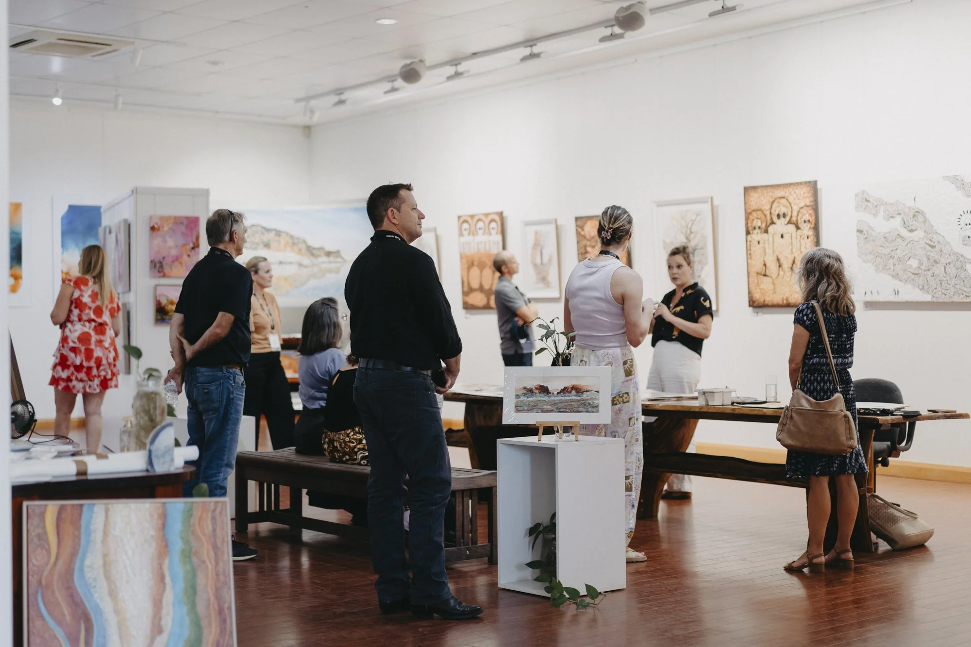 People viewing artwork and paintings at an art gallery or exhibition.