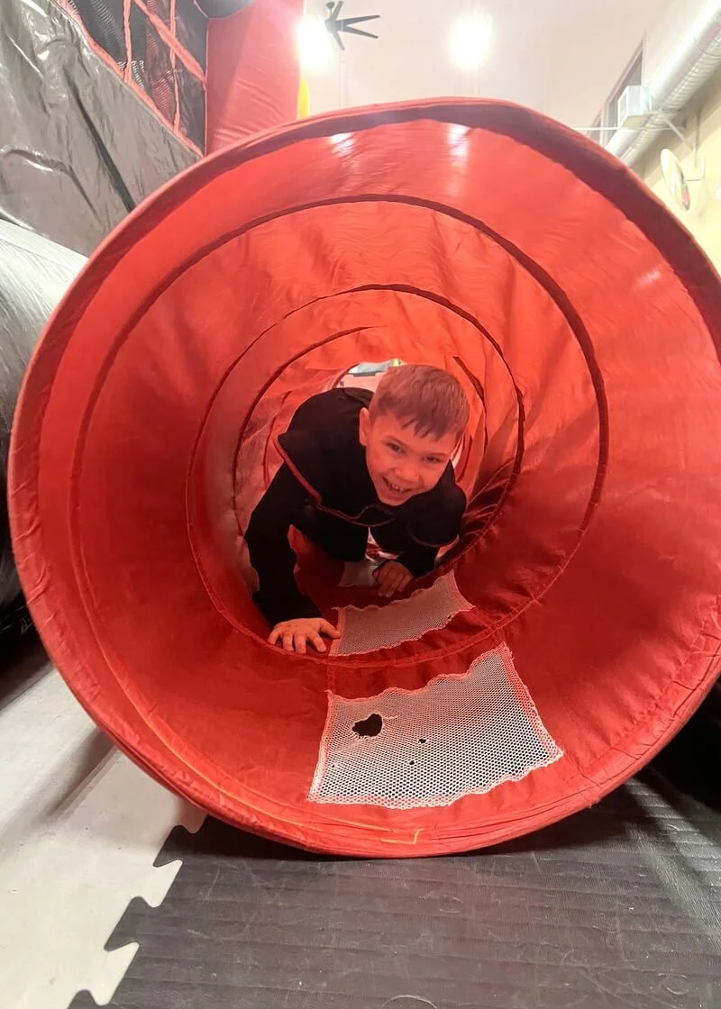 Smiling child running through obstacle course at a birthday party at Karate John's Martial Arts.