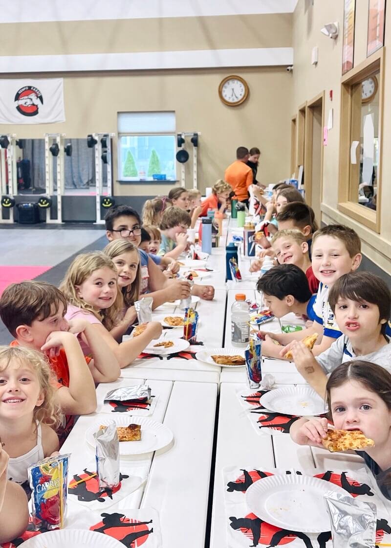 Group of kids sitting at a birthday party at Karate John's Martial Arts centers in Cicero and Liverpool, NY.