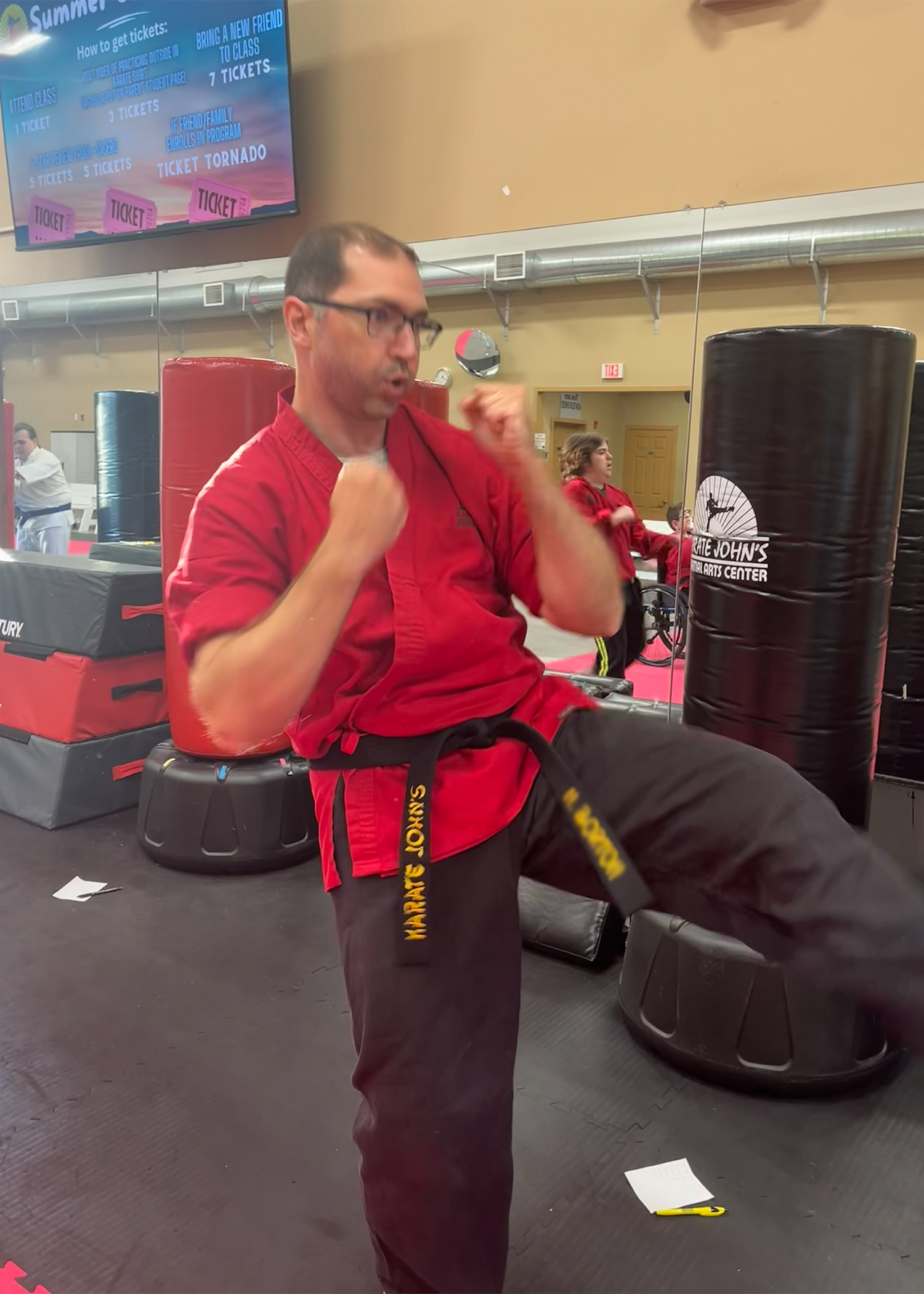 Adults having fun sparring on a kicking bag in a martial arts class at Karate John's in Cicero, NY and Liverpool, NY.