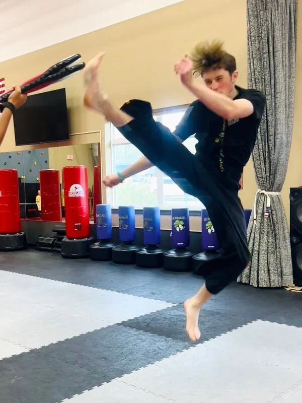 Teen boy jumping and kicking high in a martial arts and karate fitness class in Cicero and Liverpool, NY.