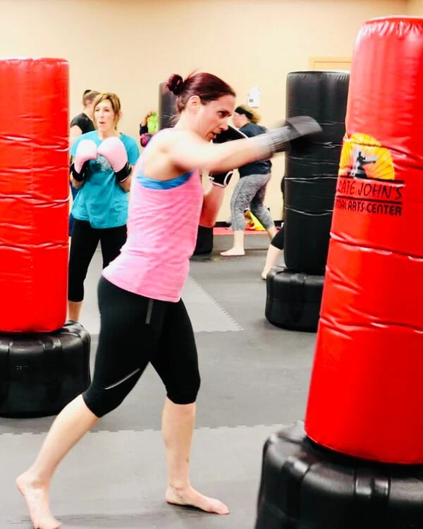 Adults having fun sparring on a kicking bag in a martial arts class at Karate John's in Cicero, NY and Liverpool, NY.