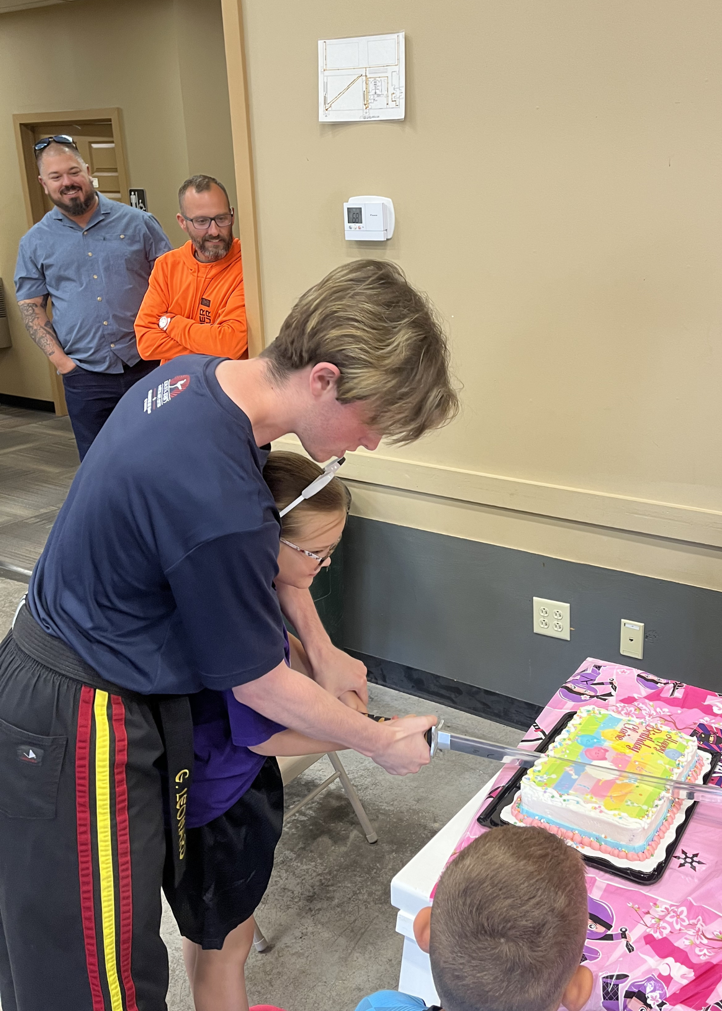 Child cutting birthday cake with a samurai sword at Karate John's Martial Arts in Cicero, NY and Liverpool, NY.
