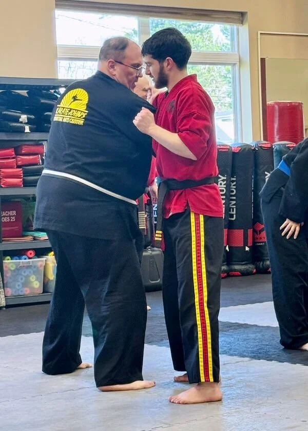 Adults practicing partner self-defense techniques during a karate class at Karate John’s Martial Arts Center in Cicero and Liverpool, NY.