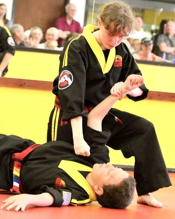 Teen girl practicing self-defense and take-down with her teen partner in a karate class in Cicero and Liverpool, NY.