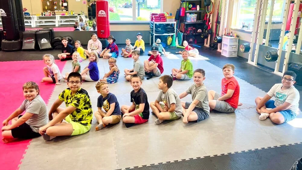 Group of kids sitting and smiling at Karate John's summer camp in Cicero, NY.