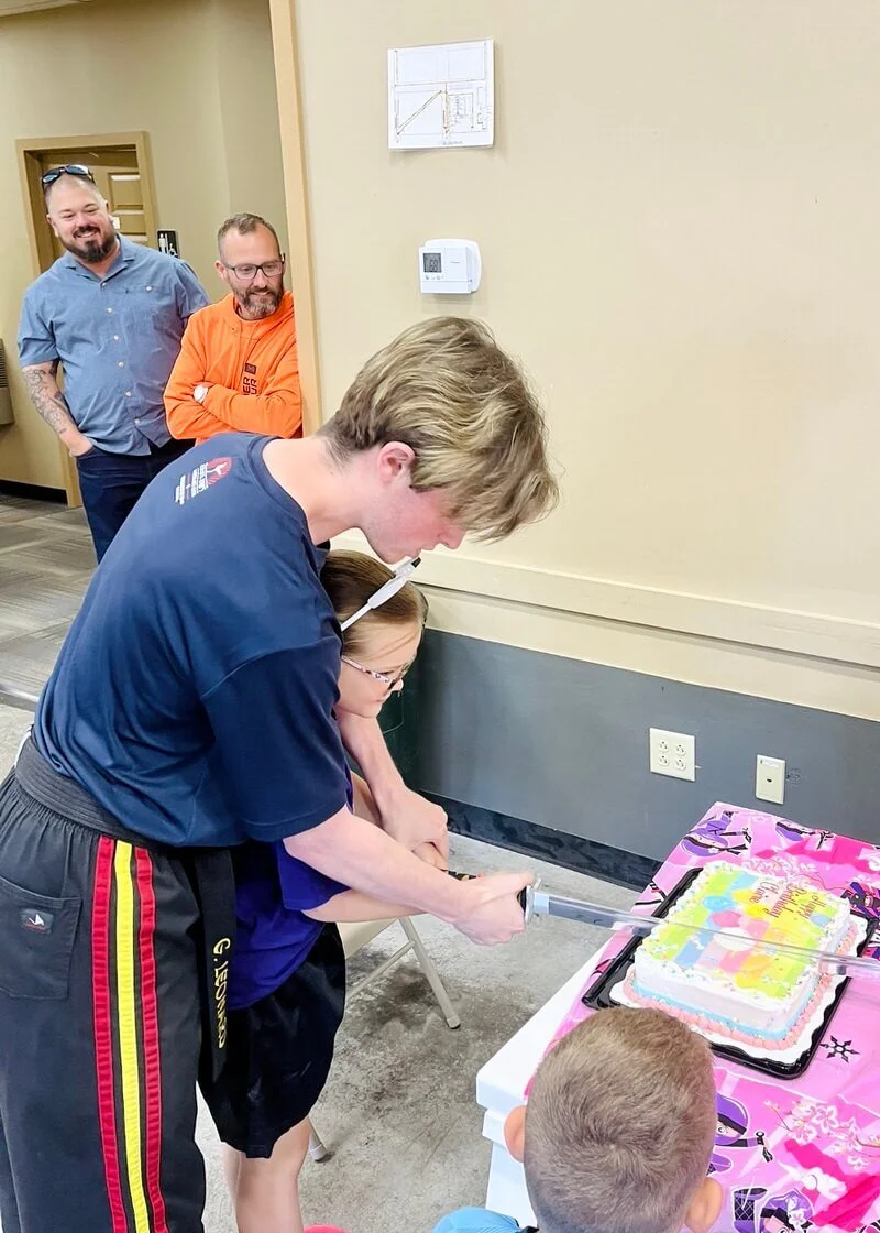 Child cutting birthday cake with a samurai sword at Karate John's Martial Arts in Cicero, NY and Liverpool, NY.