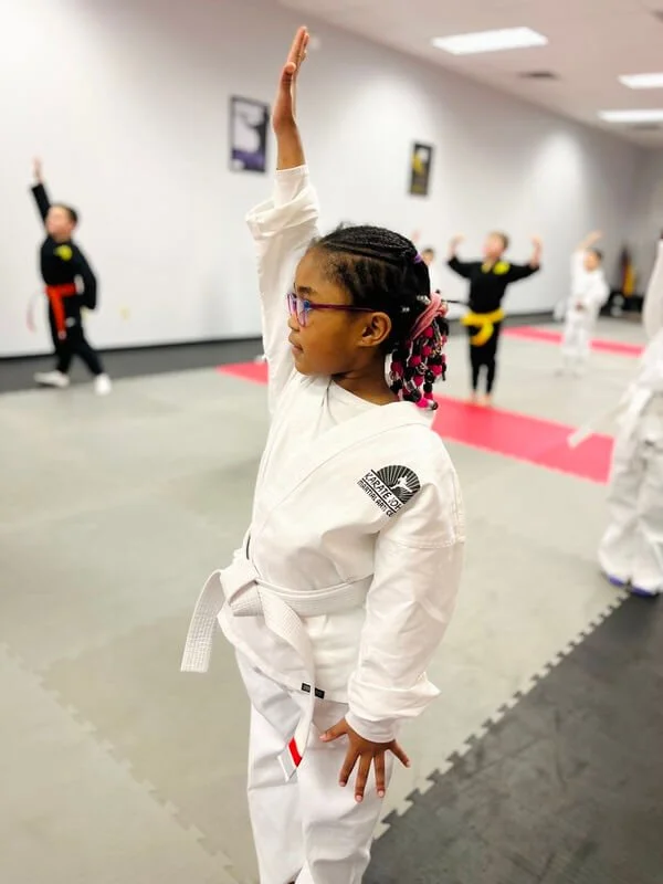 Focused girl raising hand in a kenpo karate martial arts class in Cicero, Liverpool, NY.