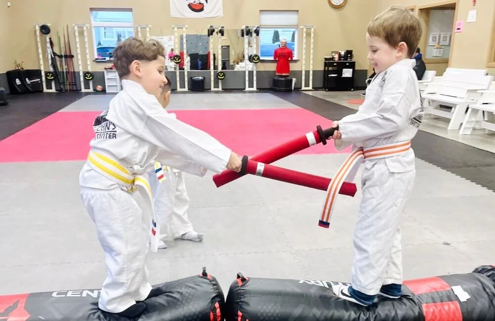 Two boys sword fighting with foam swords at a birthday party at Karate John's Martial Arts.