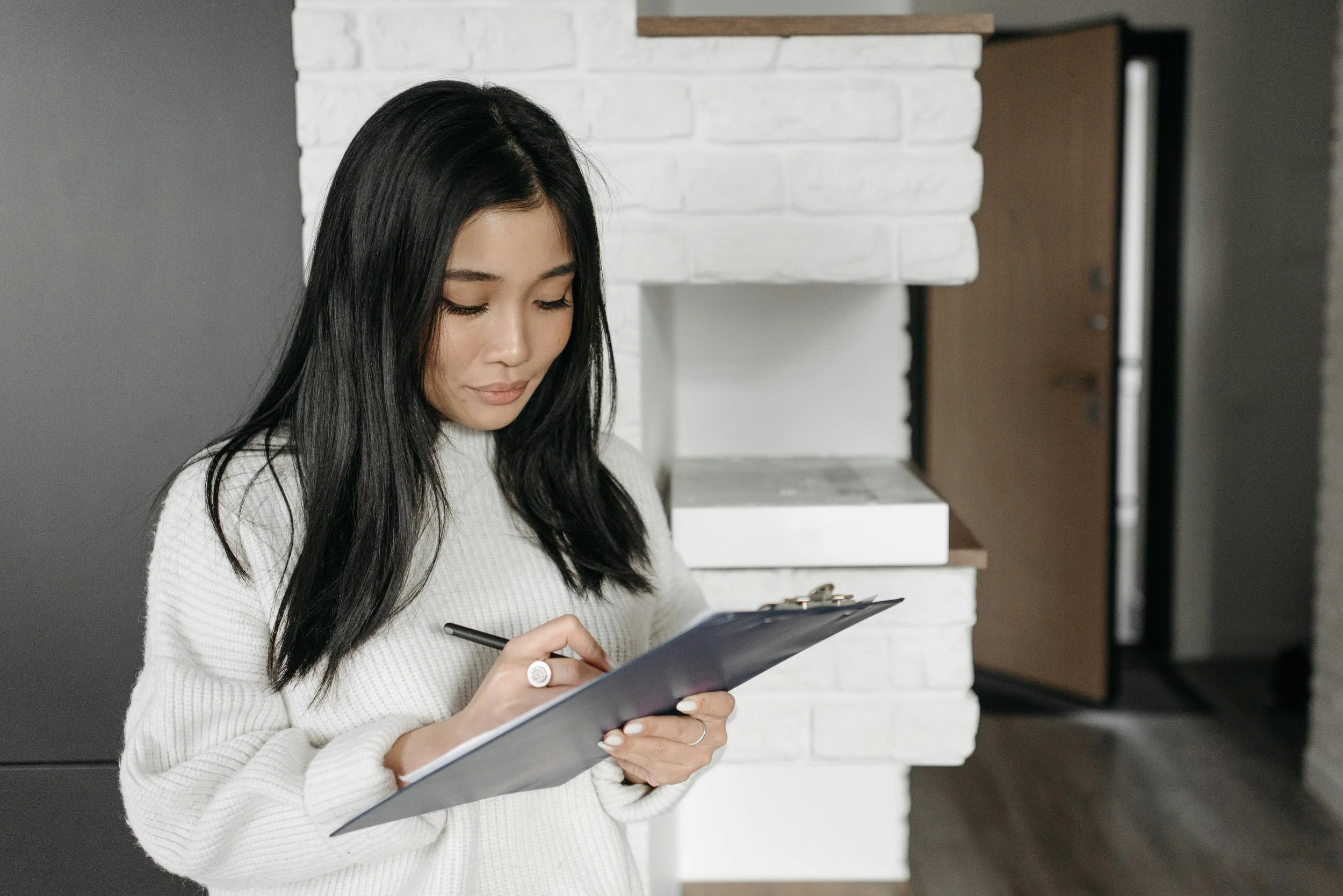 Woman standing writing notes after a Telehealth session.