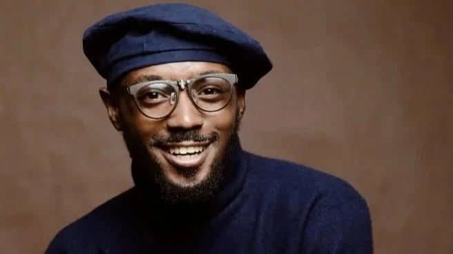 black man with glasses and a blue hat, smiling