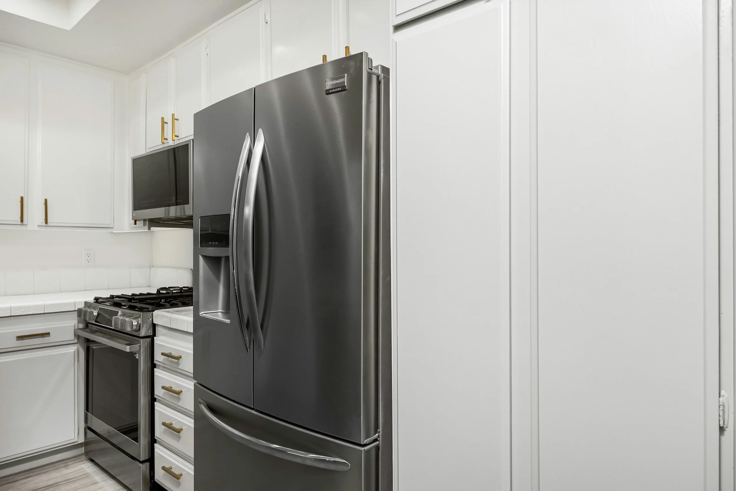 Kitchen with white cabinets, stainless steel refrigerator, microwave, and stove.