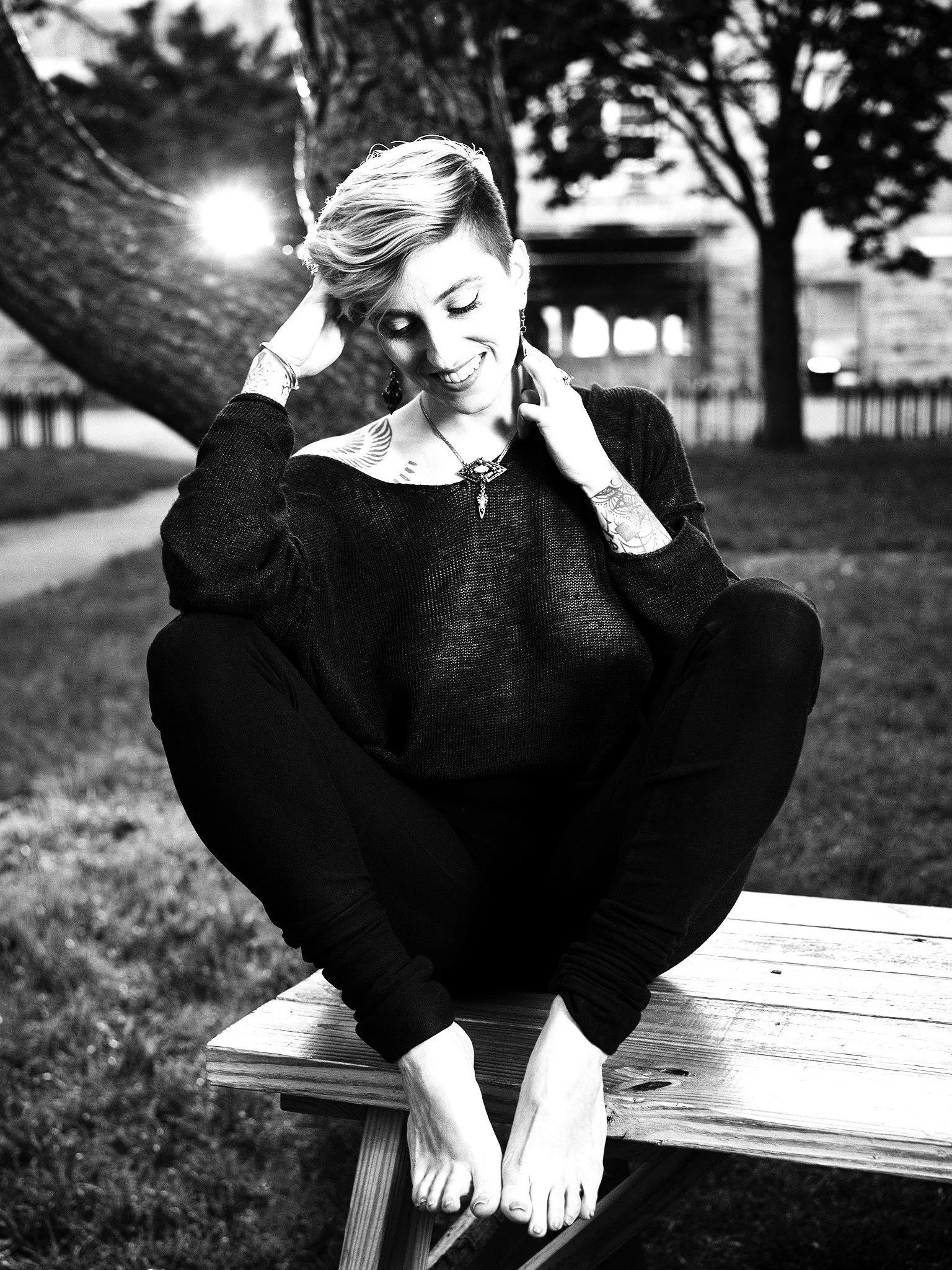 Black and white photo of Queer Artist Tashi Palmo sitting on a picnic table.