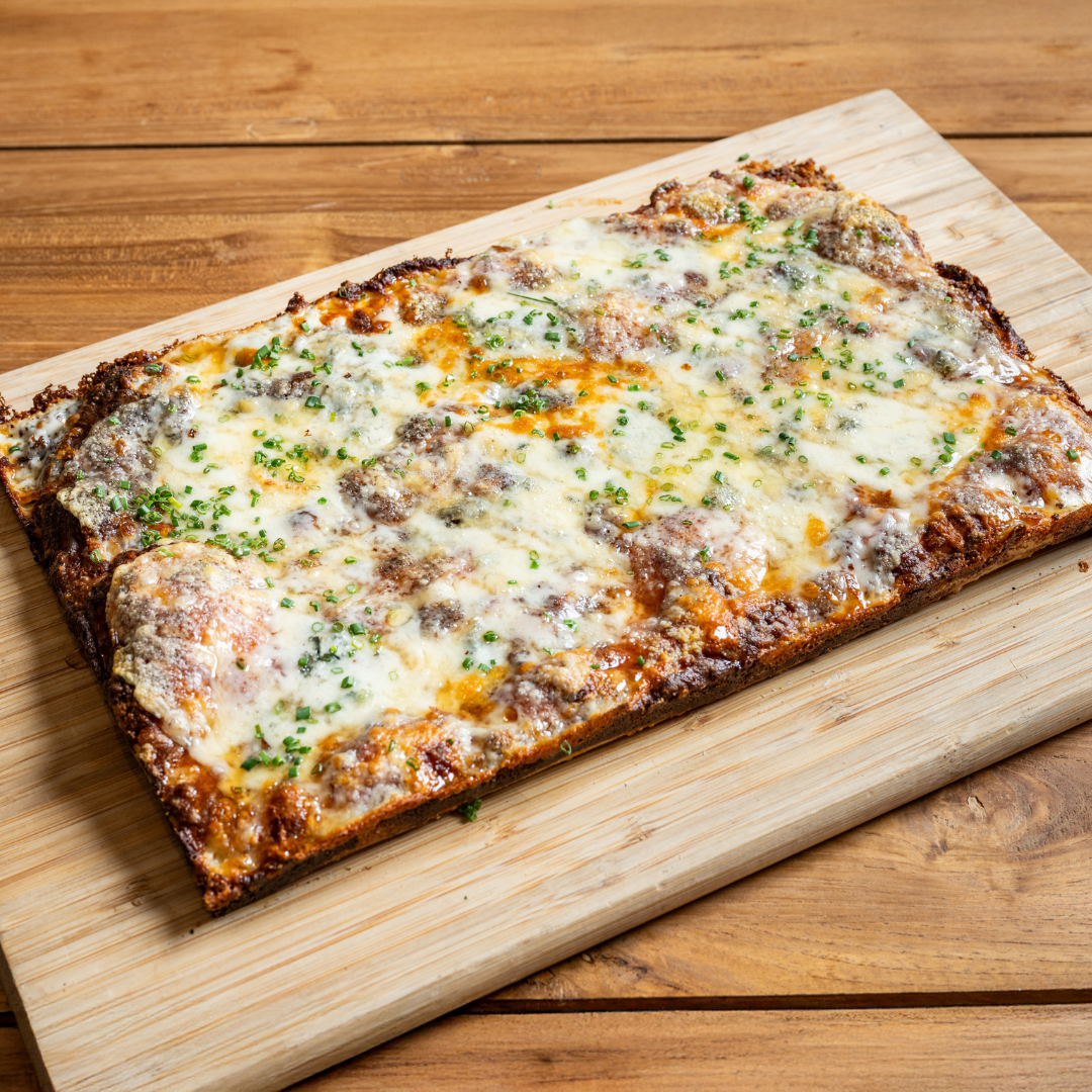 9MILE Detroit Style Square Pizza with cheese and green herbs on a wooden board.