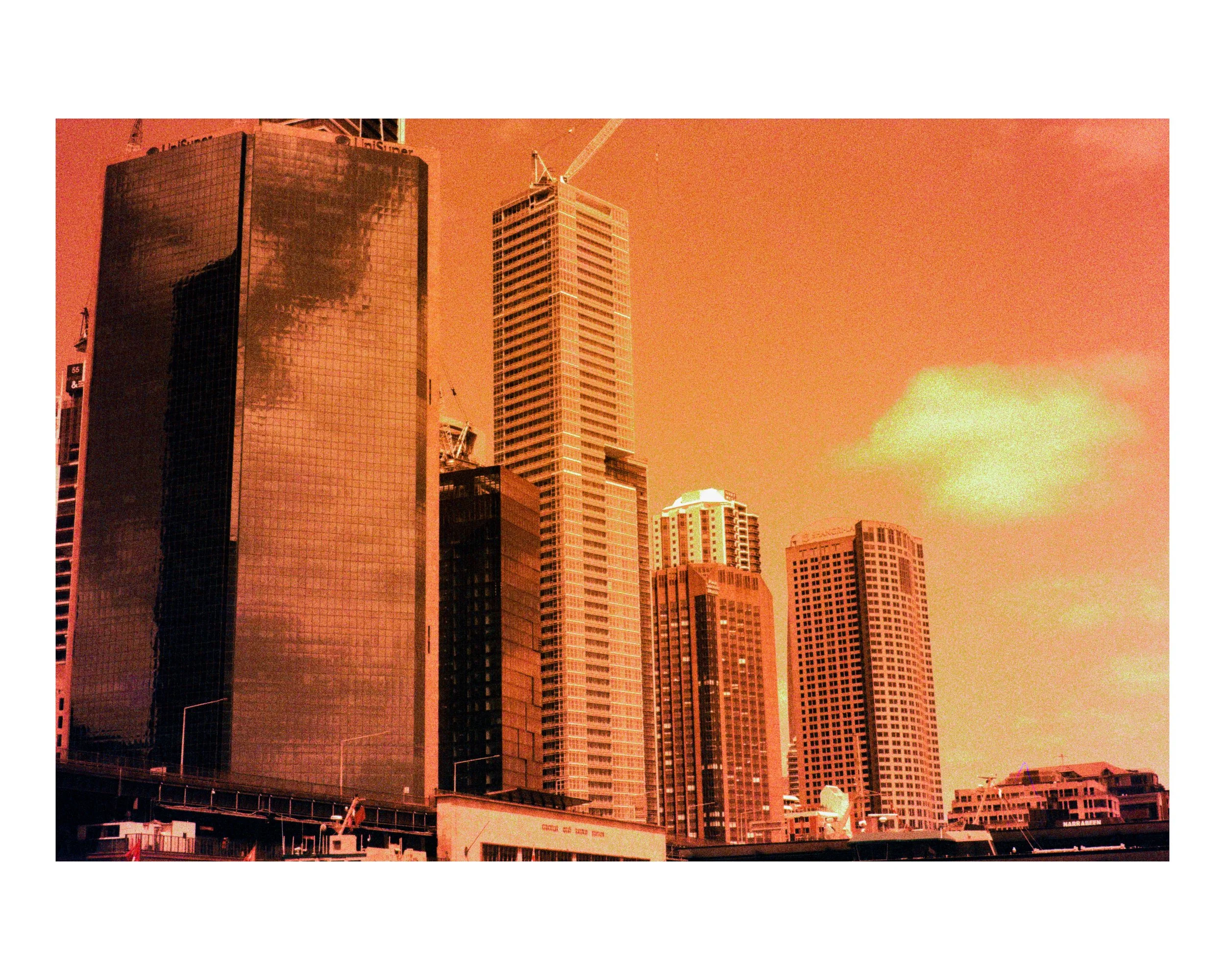 Skyscrapers in a city with an orange sky and clouds.