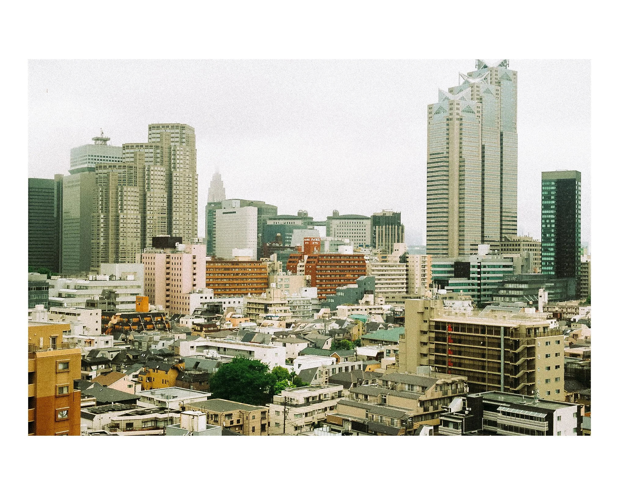 City skyline with a mix of low-rise and high-rise buildings, some tall skyscrapers in the background, and a cloudy sky.