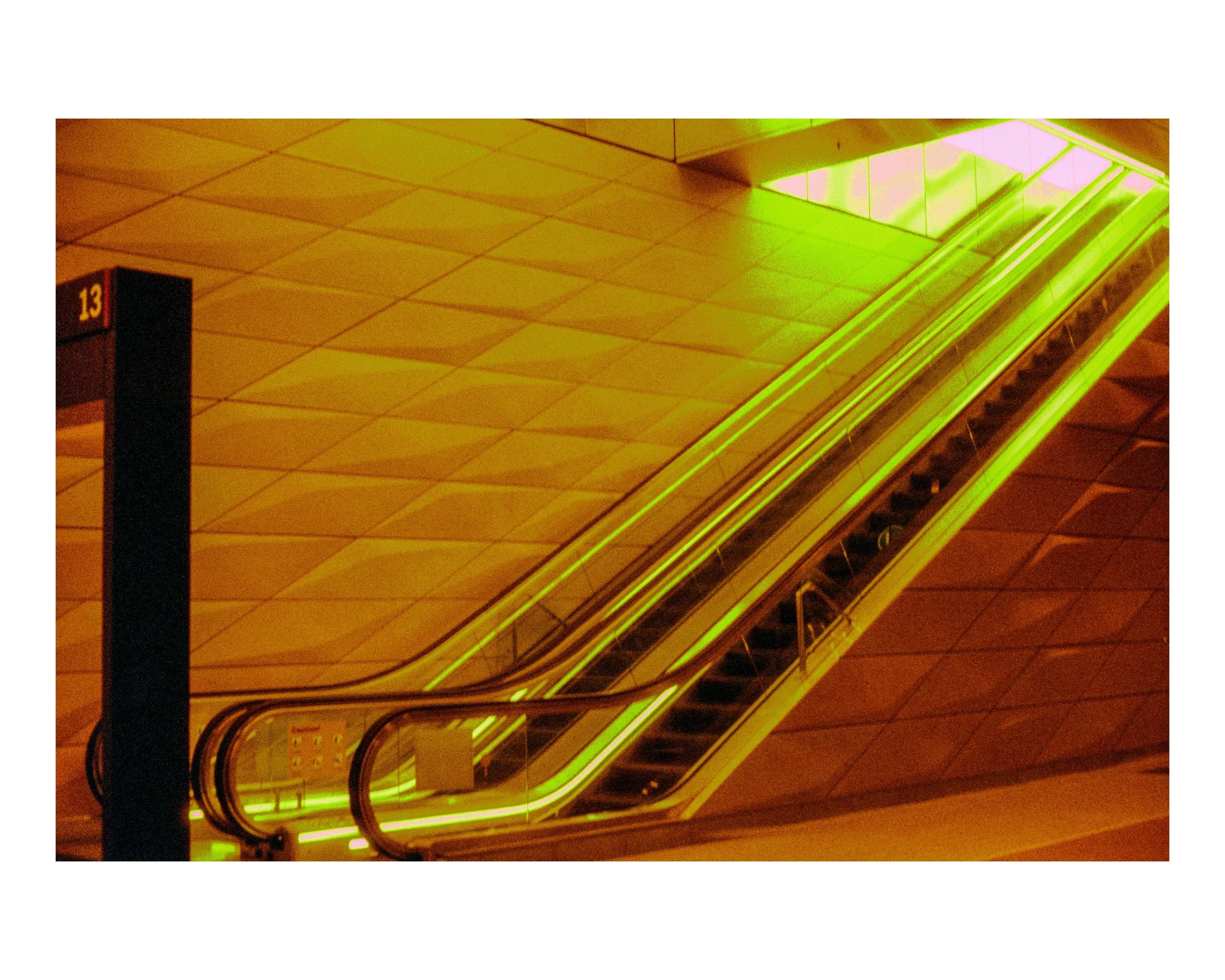 Empty escalator with green neon lights in an indoor setting.