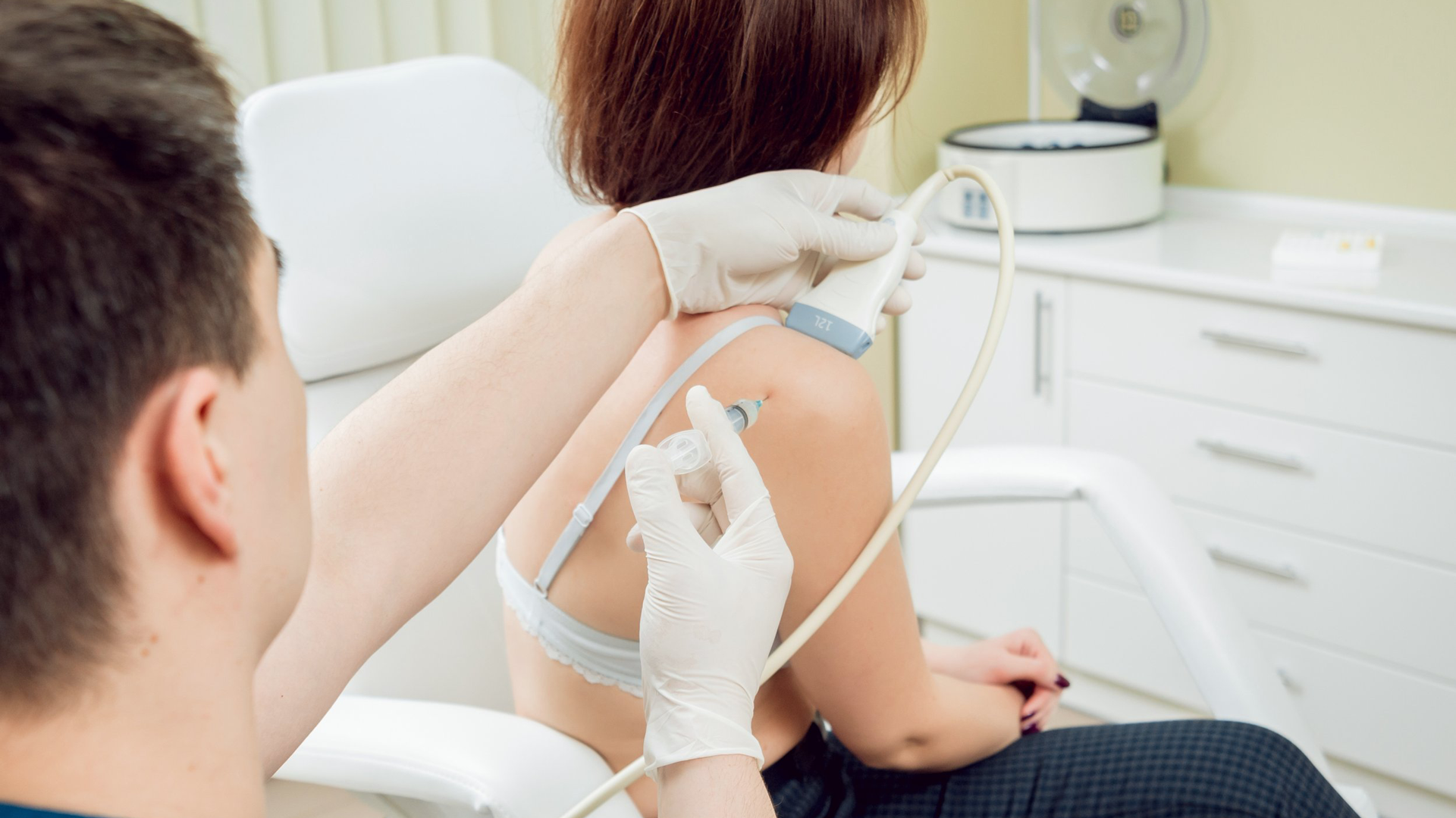 A healthcare professional administers an ultrasound guided injection in to a woman's shoulder at leigh injection clinic