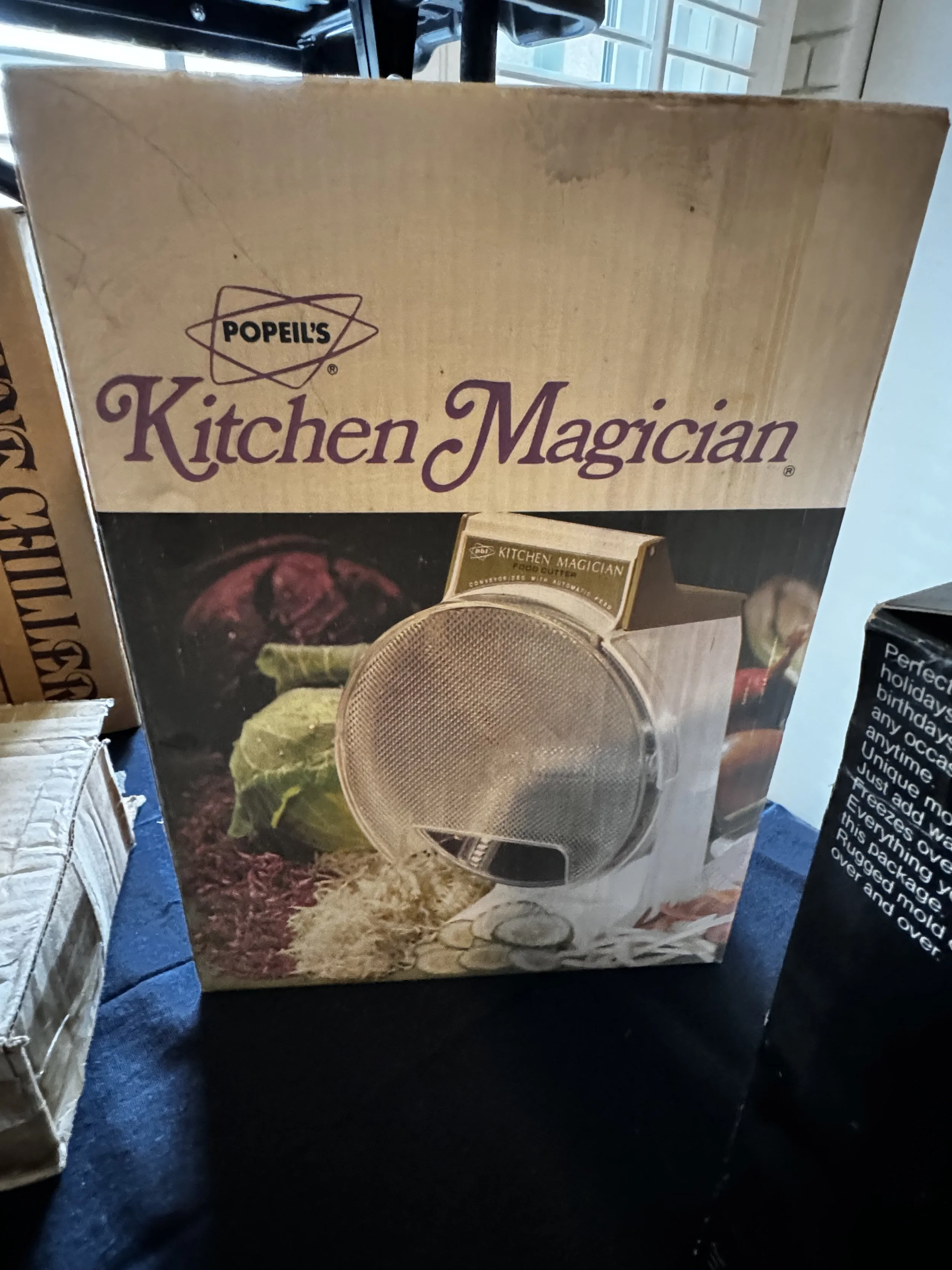 Box for Popeil's Kitchen Magician food processor with an image of the food processor and some vegetables on the front