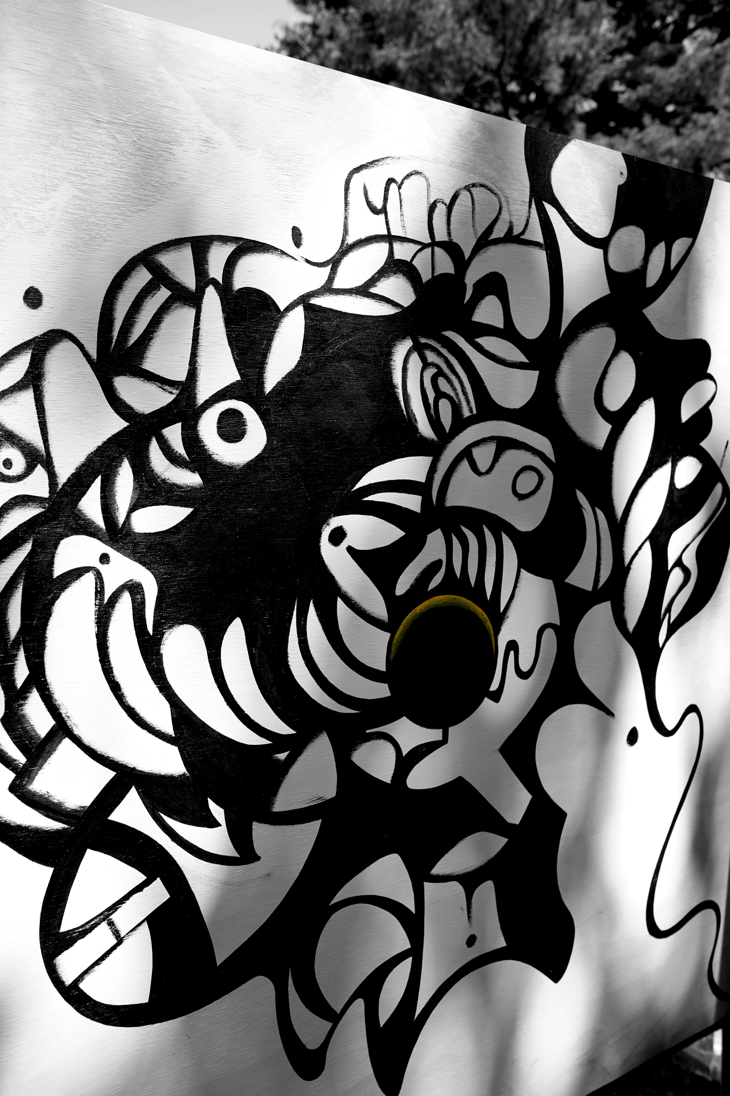 Black and white abstract graffiti art on a wall featuring bold lines and swirling shapes.