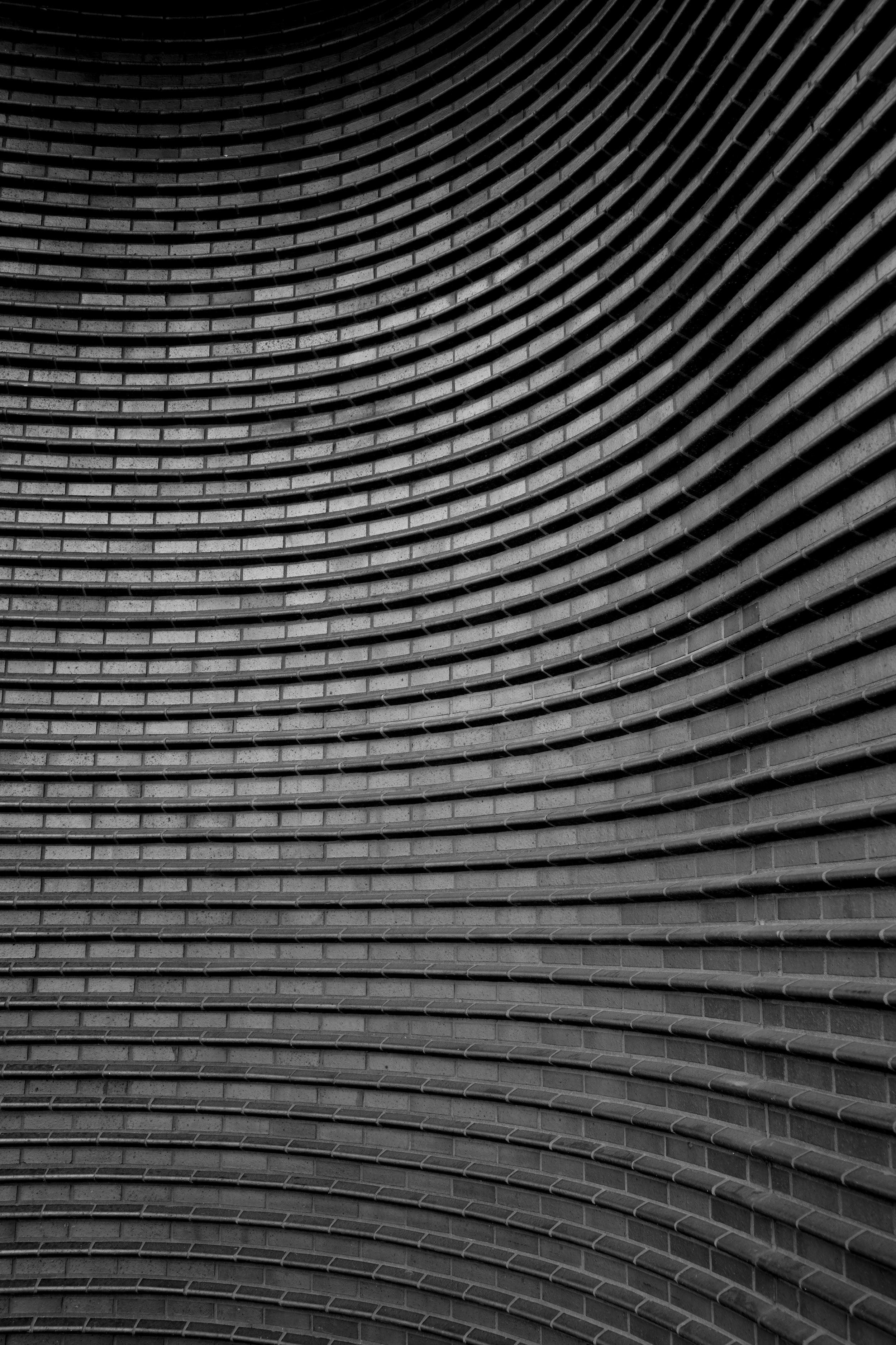 Close-up of a modern building facade with curved horizontal lines and brick surface in black and white.