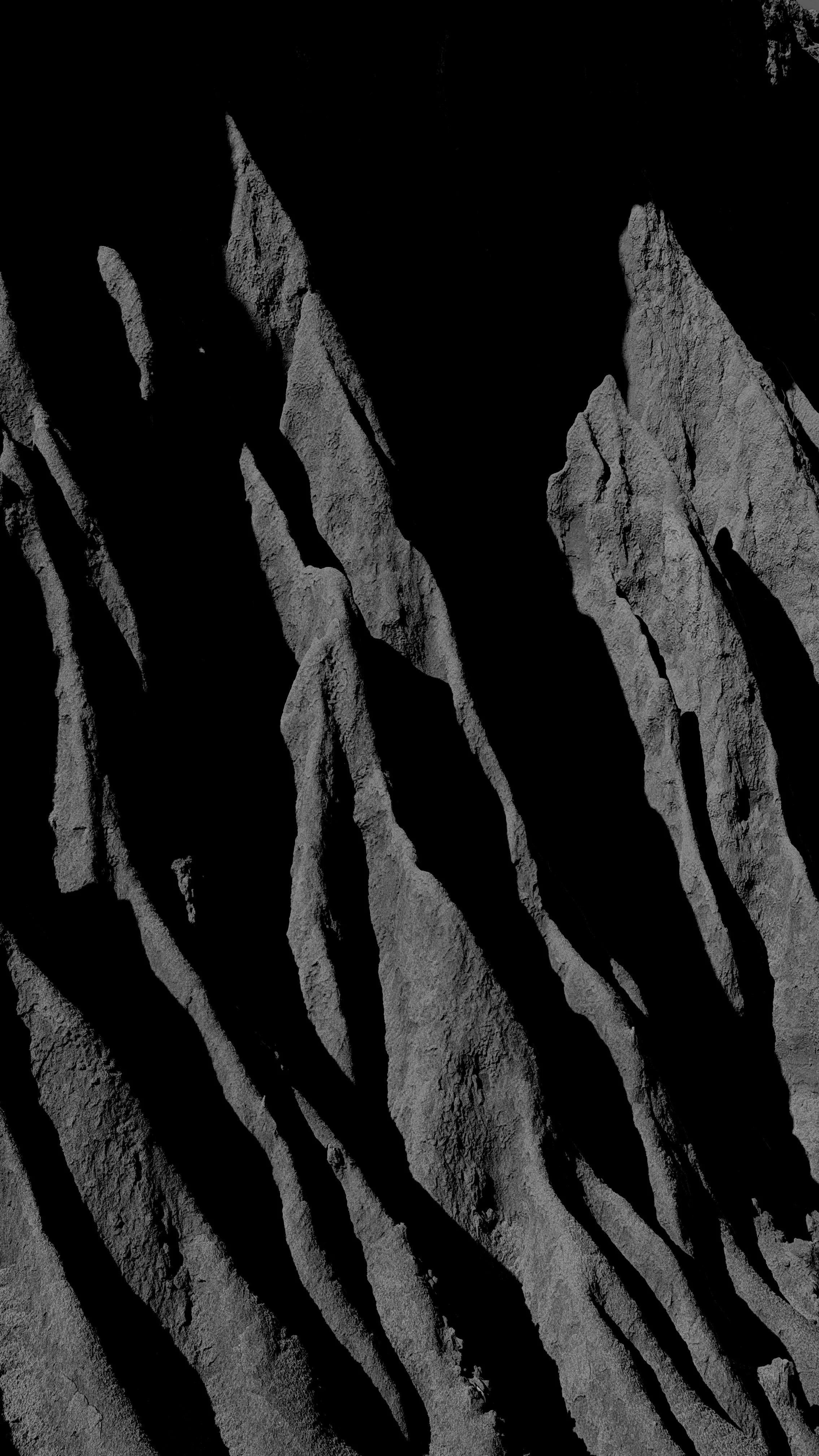 Gray rock formations with sharp, jagged peaks and deep shadows, creating a dramatic landscape.