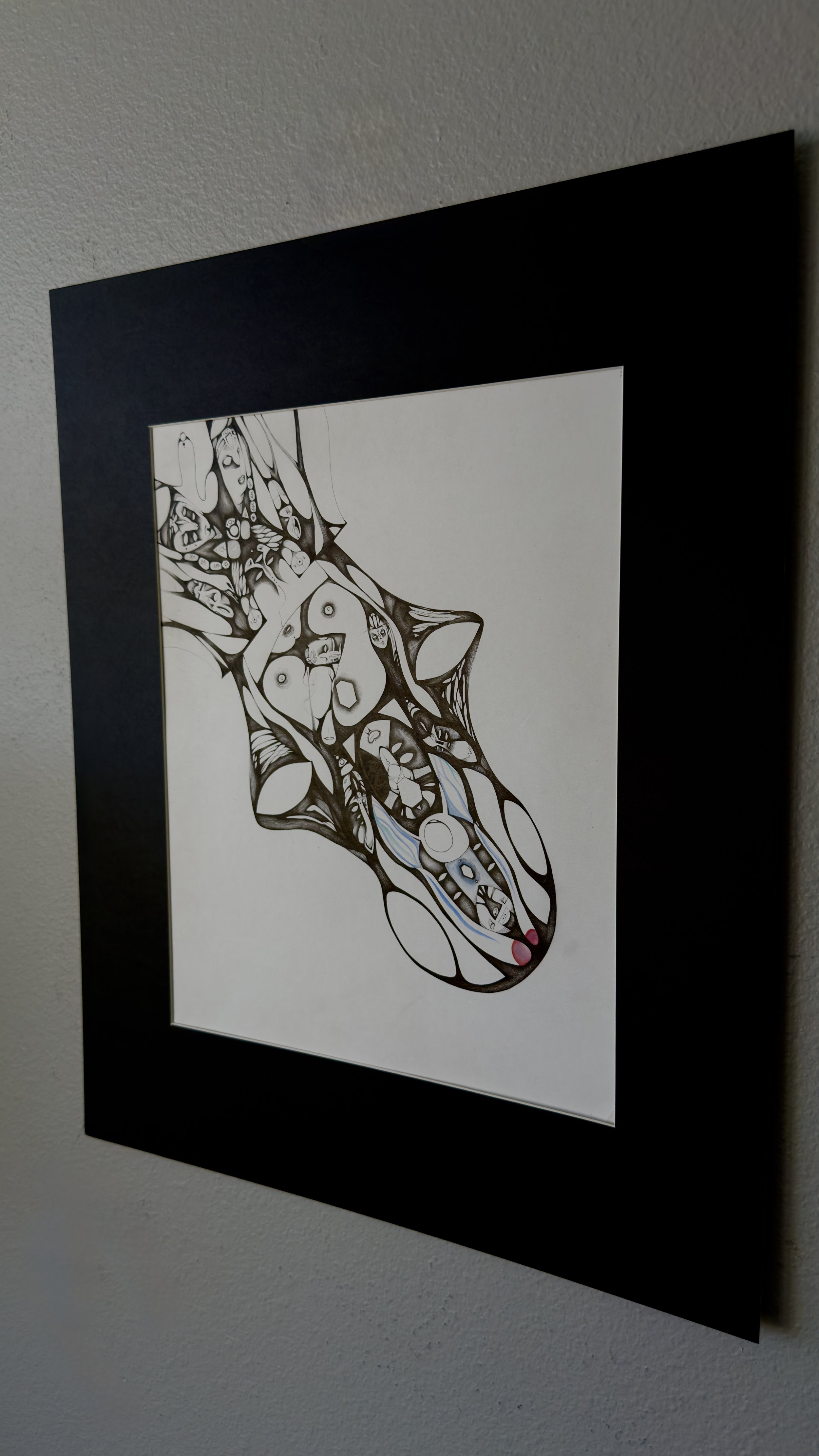 Black, white, shades of blue, and shades of red abstract art with interconnected shapes and patterns, including circles, triangles, and lines, framed in a black border on a white wall.