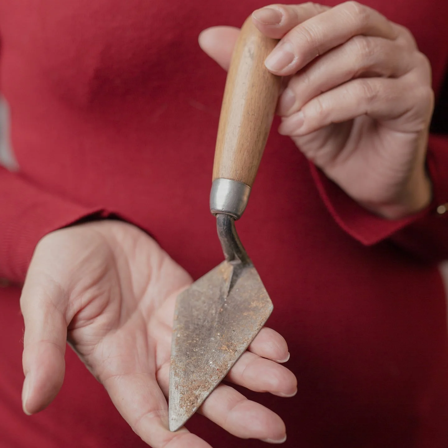 A person holding a small chisel and a hammer, working on a piece of stone or wood.