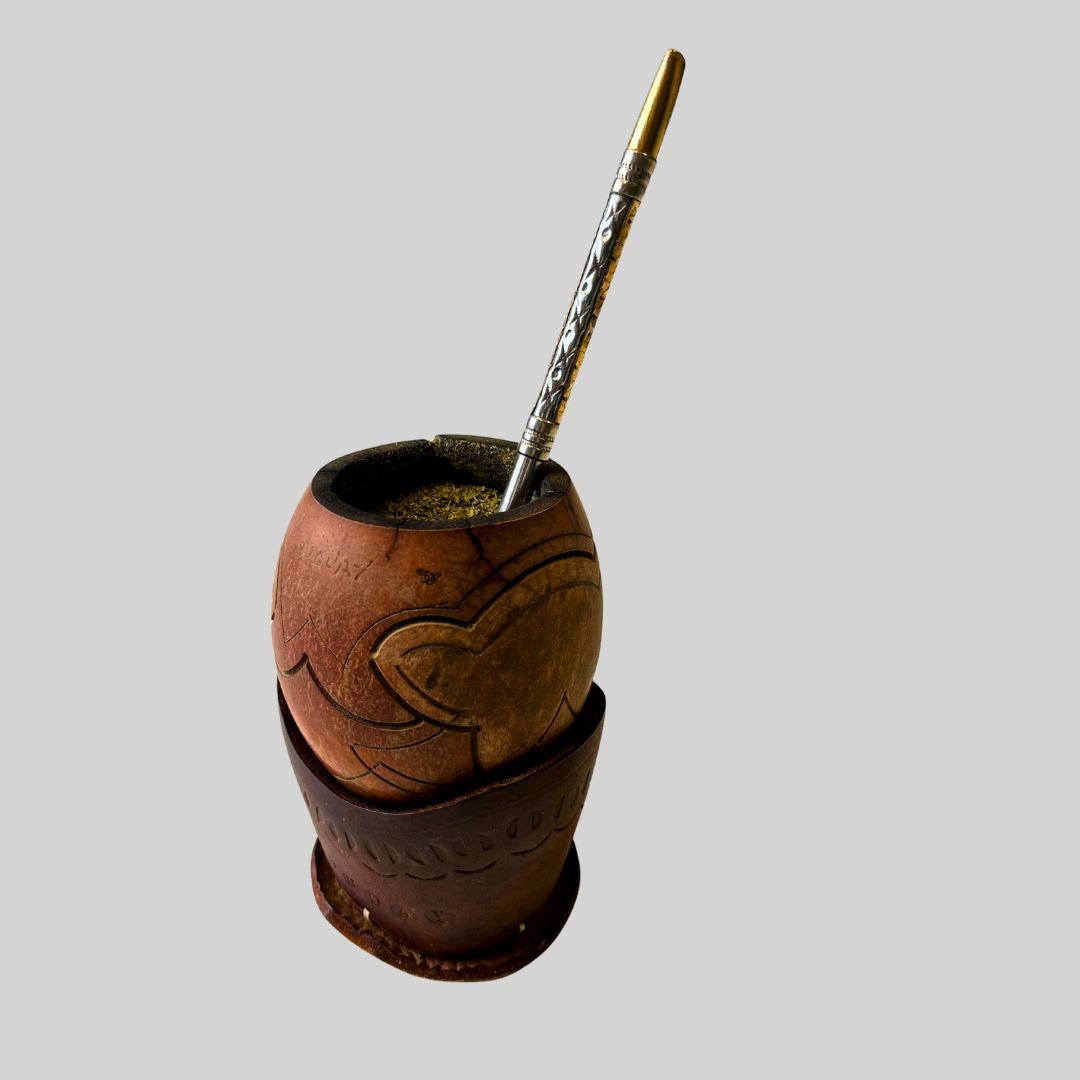 A traditional mate gourd with a metal straw and a decorative pen inside.
