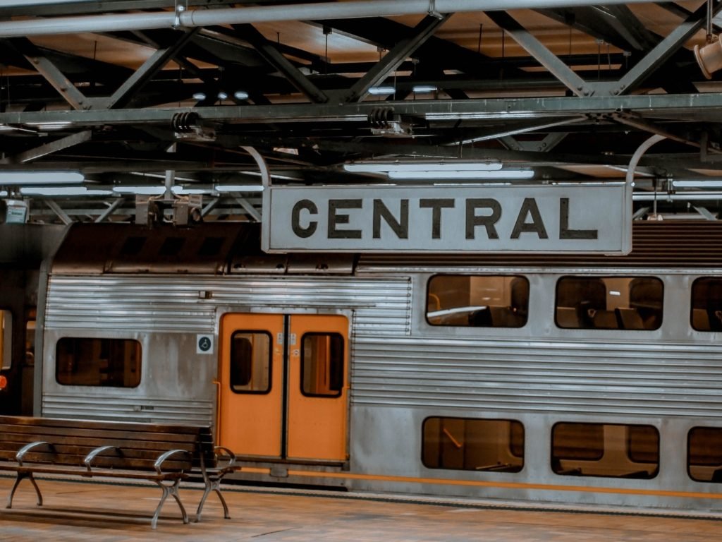 Amtrak train at a station with a sign that says 'Central' and empty benches in the foreground.